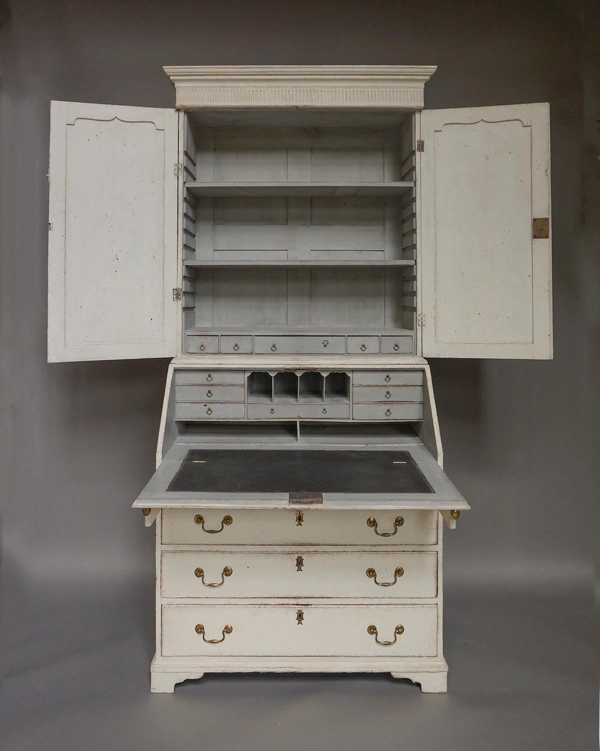 Gustavian period secretary, Sweden circa 1790, in two parts. The upper section has a simple cornice with reeded detail over two doors with shaped, recessed panels. The interior has two adjustable shelves and five small drawers. The lower section has