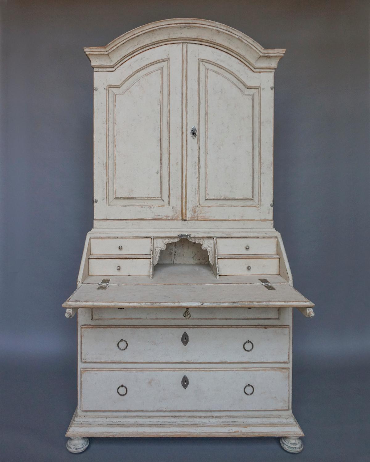 Period Gustavian secretary in two parts, Sweden, circa 1830. The upper library section has a graceful arched cornice with double raised-panel doors. Inside are three fixed shelves, the top one having a concave form with notches for spoons. The lower