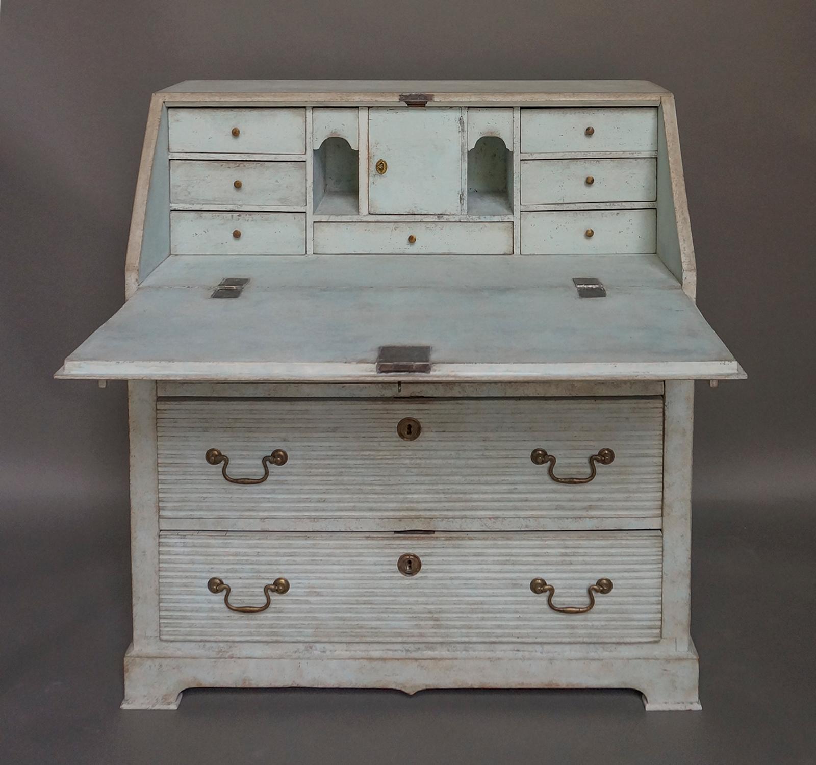 Late Gustavian slant-front writing desk, Sweden circa 1820.  The fitted interior in pale blue paint has a locking compartment and disguised drawers.  Below are three full-width reeded drawers.  The piece sits on a bracket base with exaggerated pad