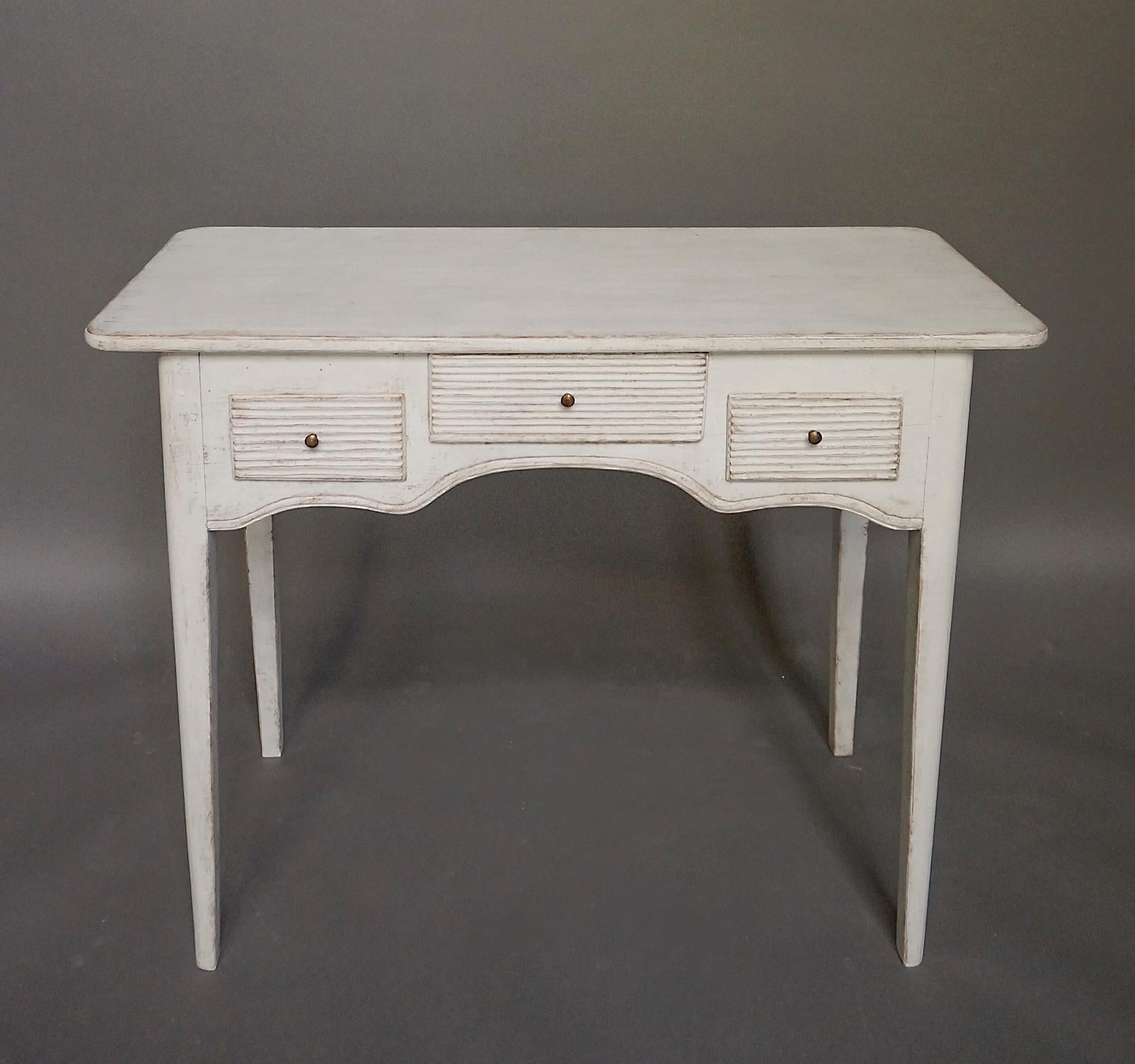 Gustavian writing table, Sweden, circa 1820. Three reeded drawers and a shaped apron with room for the writer’s knees. Tapering legs with rounded corners.