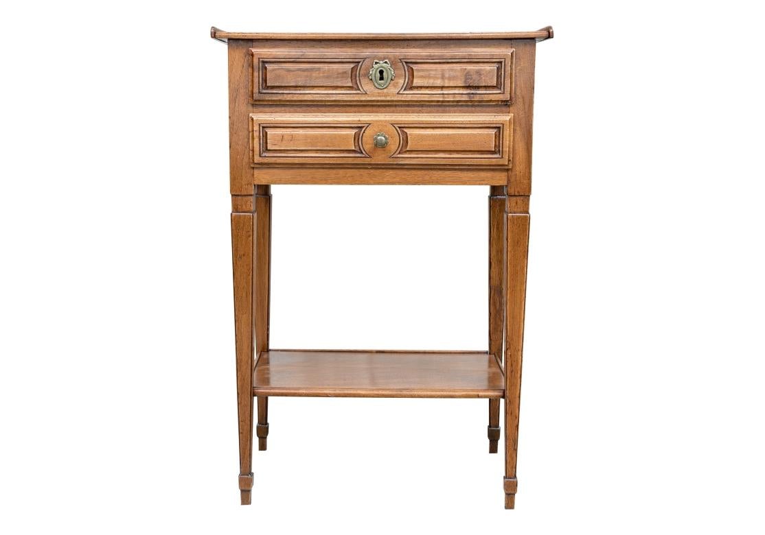 A French Antique table with soft worn wood  with tapering legs, Gallery top, dove-tail drawer construction and a particularly fine form. One drawer with a key pull (Not the original key and used for function) and Swag and Bow escutcheon, the other