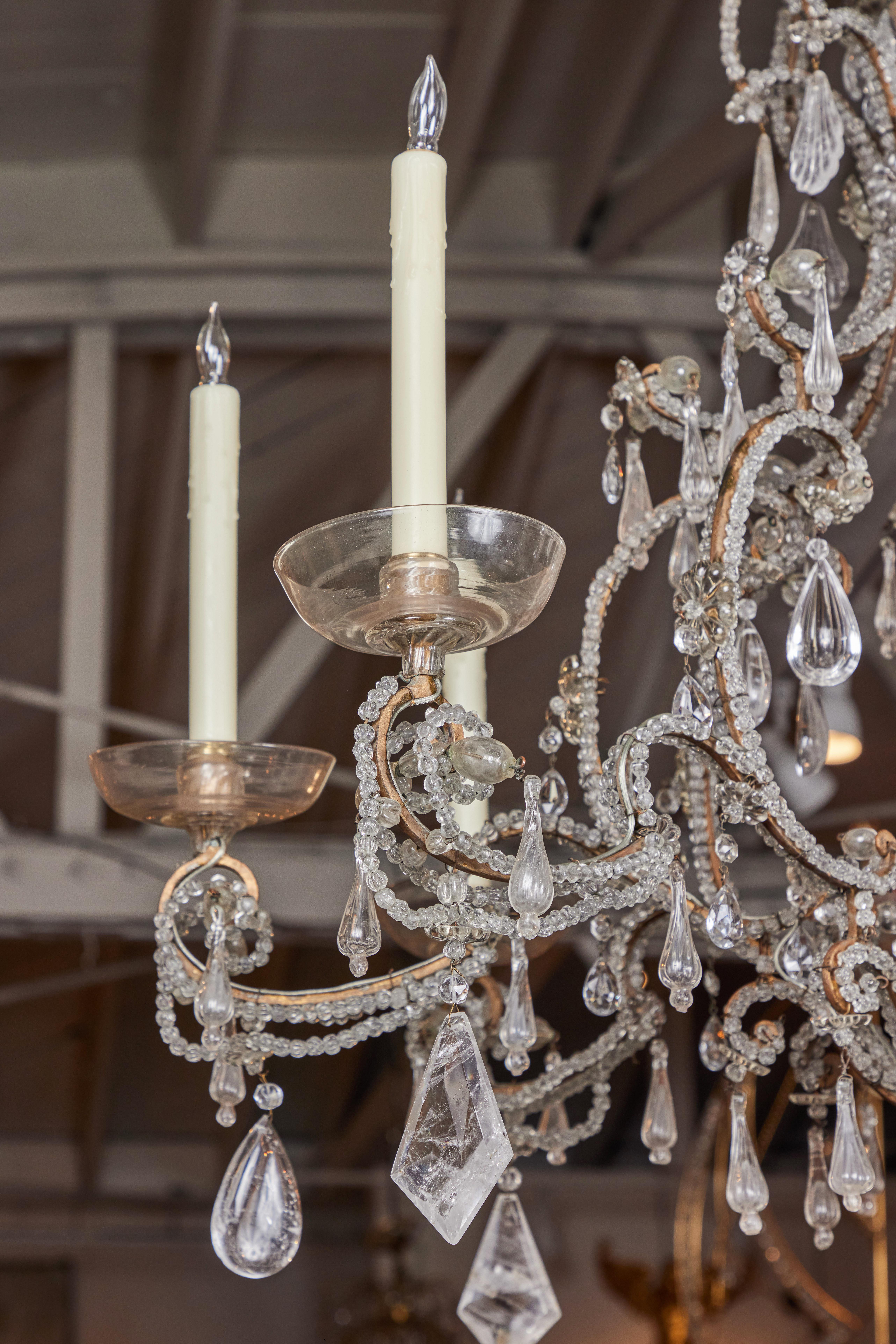 A c. 1880, eight-light chandelier from famed French maker, Maison Baguès whose work has been desired by discriminating collectors and decorators since the 1840's. This piece features a scrolling, gilded carriage covered in crystal beads and richly