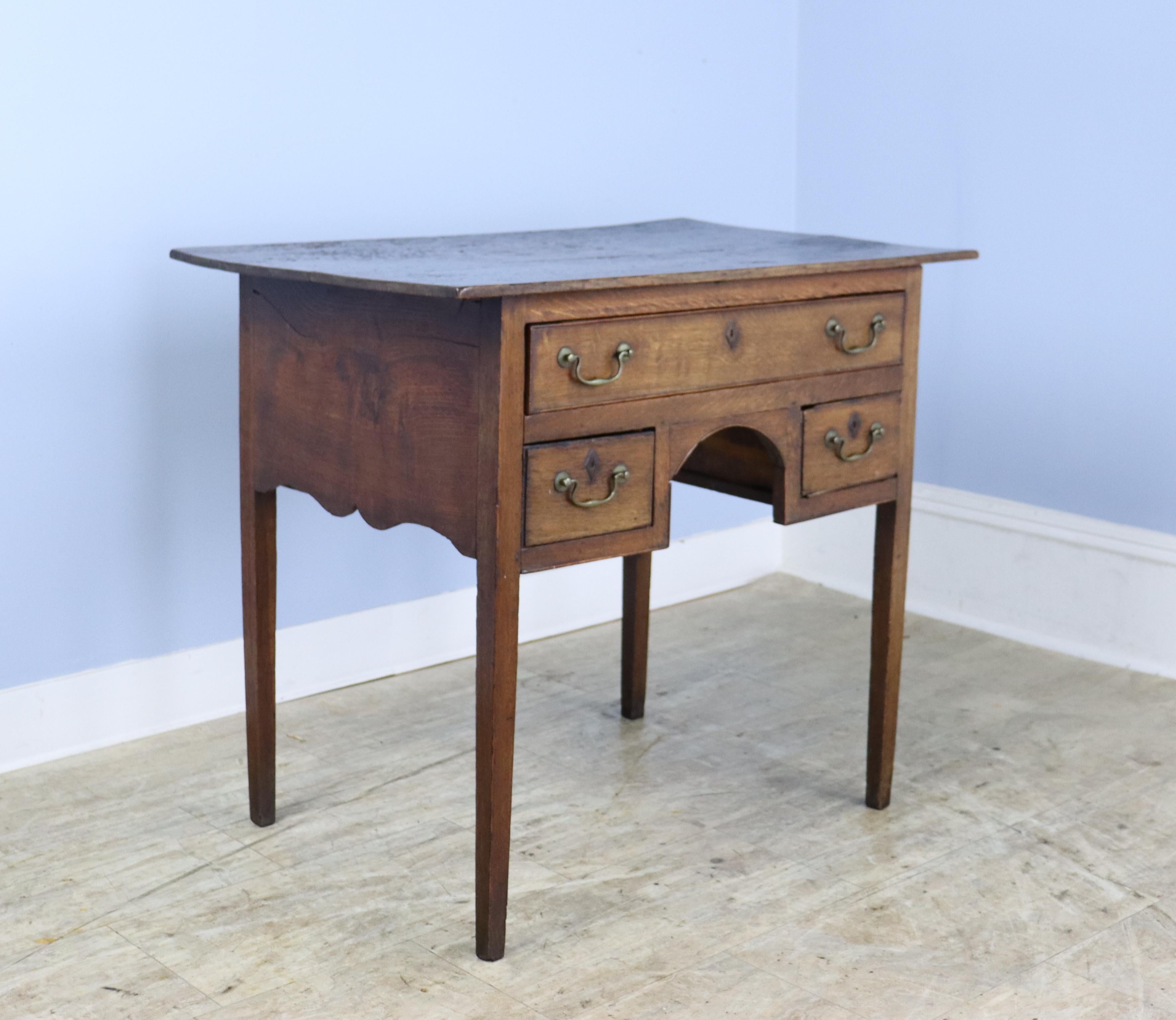 An early period oak lowboy with a glossy patinated natural grained top that we rarely see.  Good oak color and classic lowboy construction.  The three drawers open and close easily, though a bit of the cockbeading has come off around one of the