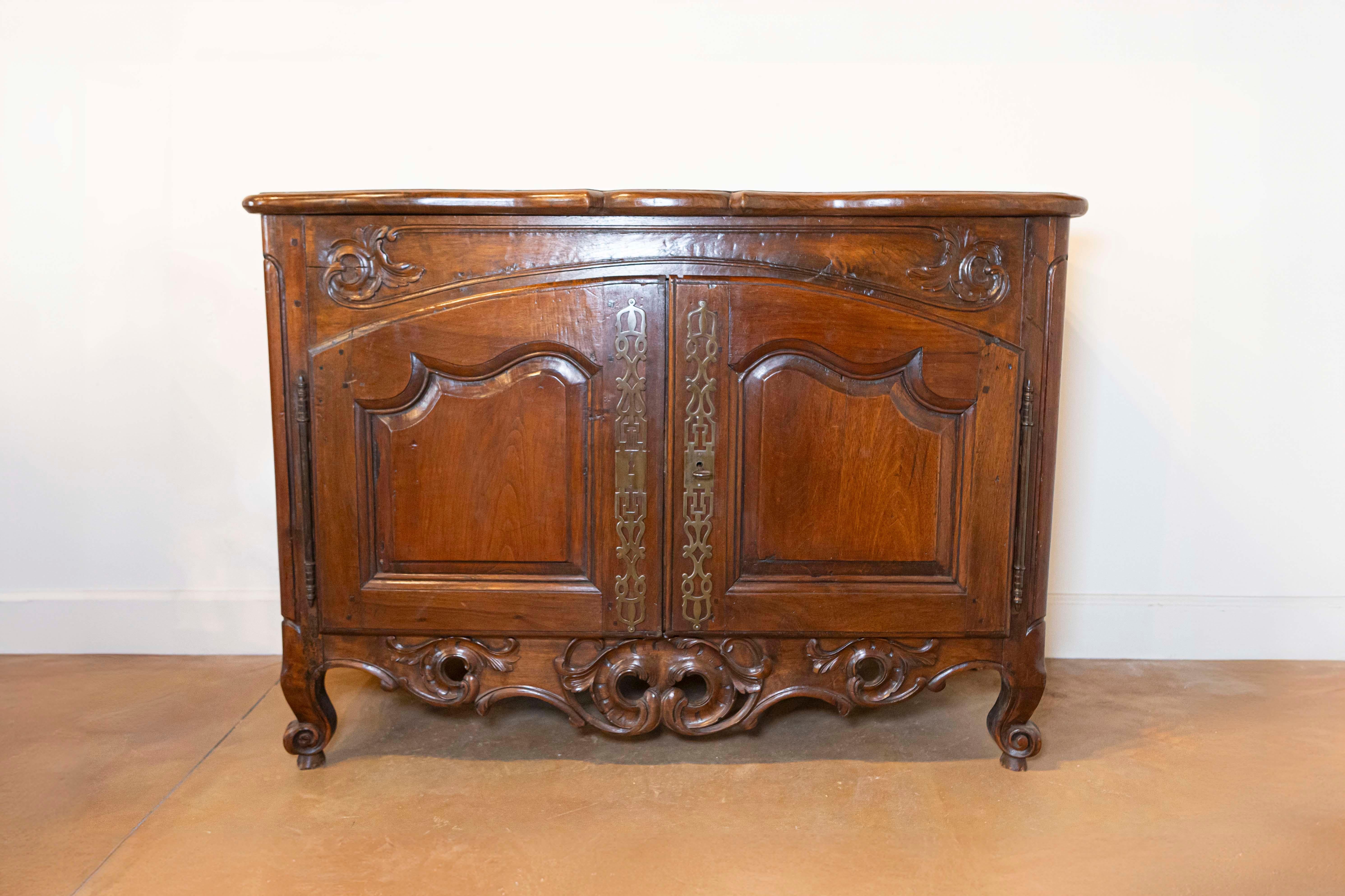 Bufé de nogal de la época francesa Regence de principios del siglo XVIII con faldón tallado y herrajes originales de Lyon. Este bufé francés de dos puertas de nogal nació en la década de 1720 en Lyon, capital de la región francesa de Ródano-Alpes,