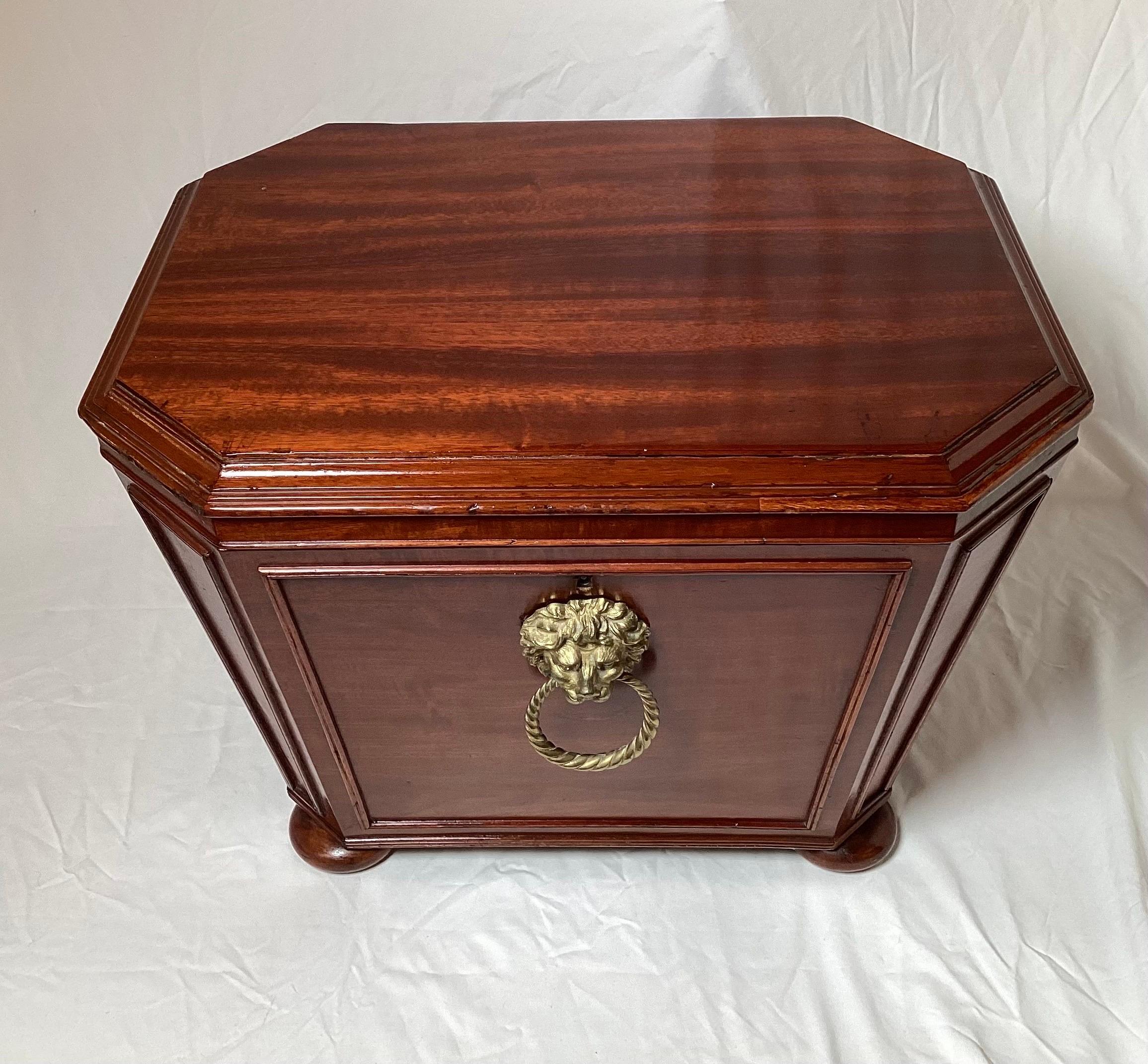 Elegant solid mahogany diminutive wine cellarette chest. The flat top lid with panel sided of tapering form with a large lion head ring pull. The interior with a felt lined top, the dividers have long since been removed to make this a functional