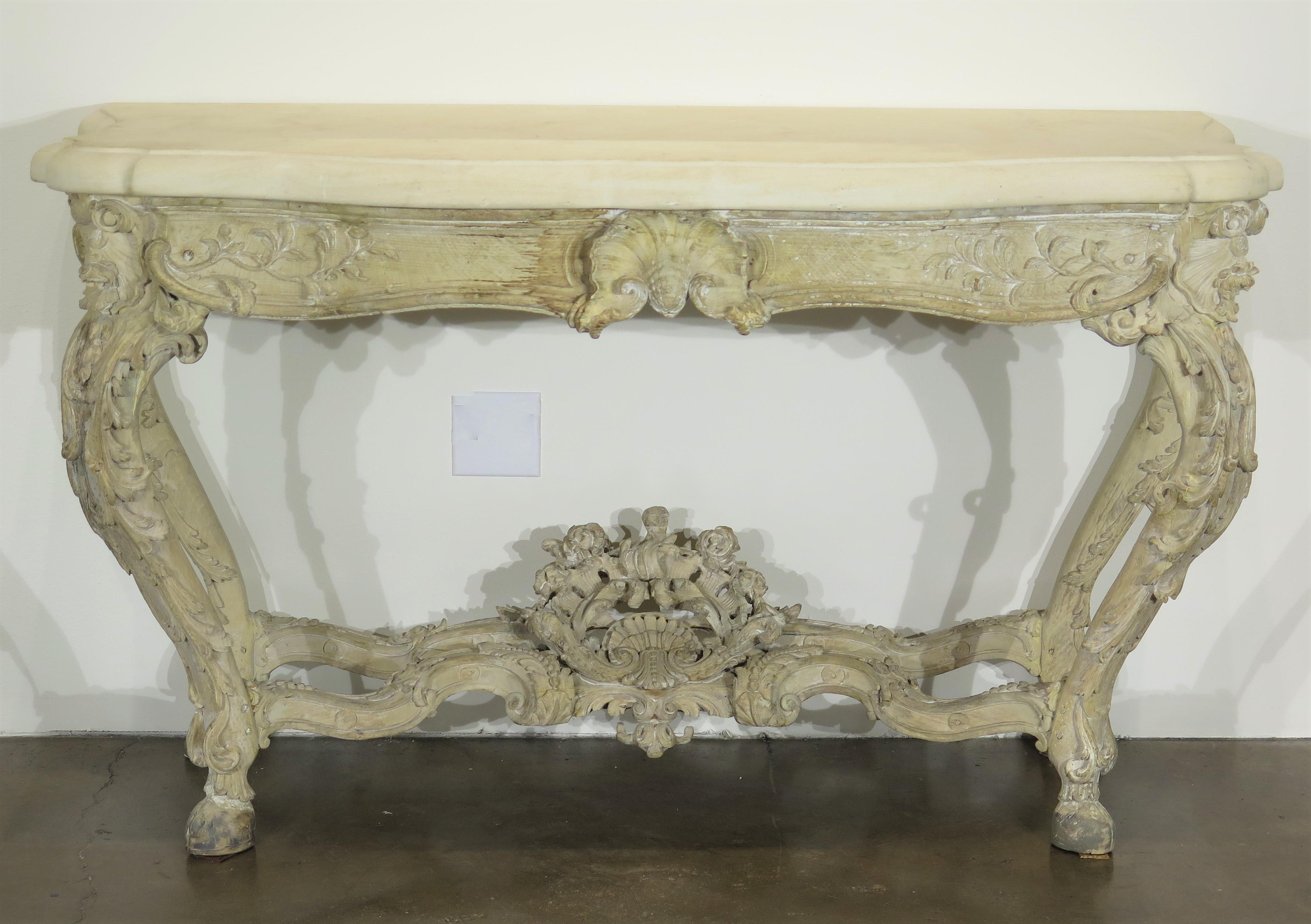 period Rococo / Louis XV large scale / grand elaborately carved and painted console table with swirls, leaves, and shells, cabriole legs with cloven hoof feet, shaped limestone top (added later), French. 18th century, circa 1730 