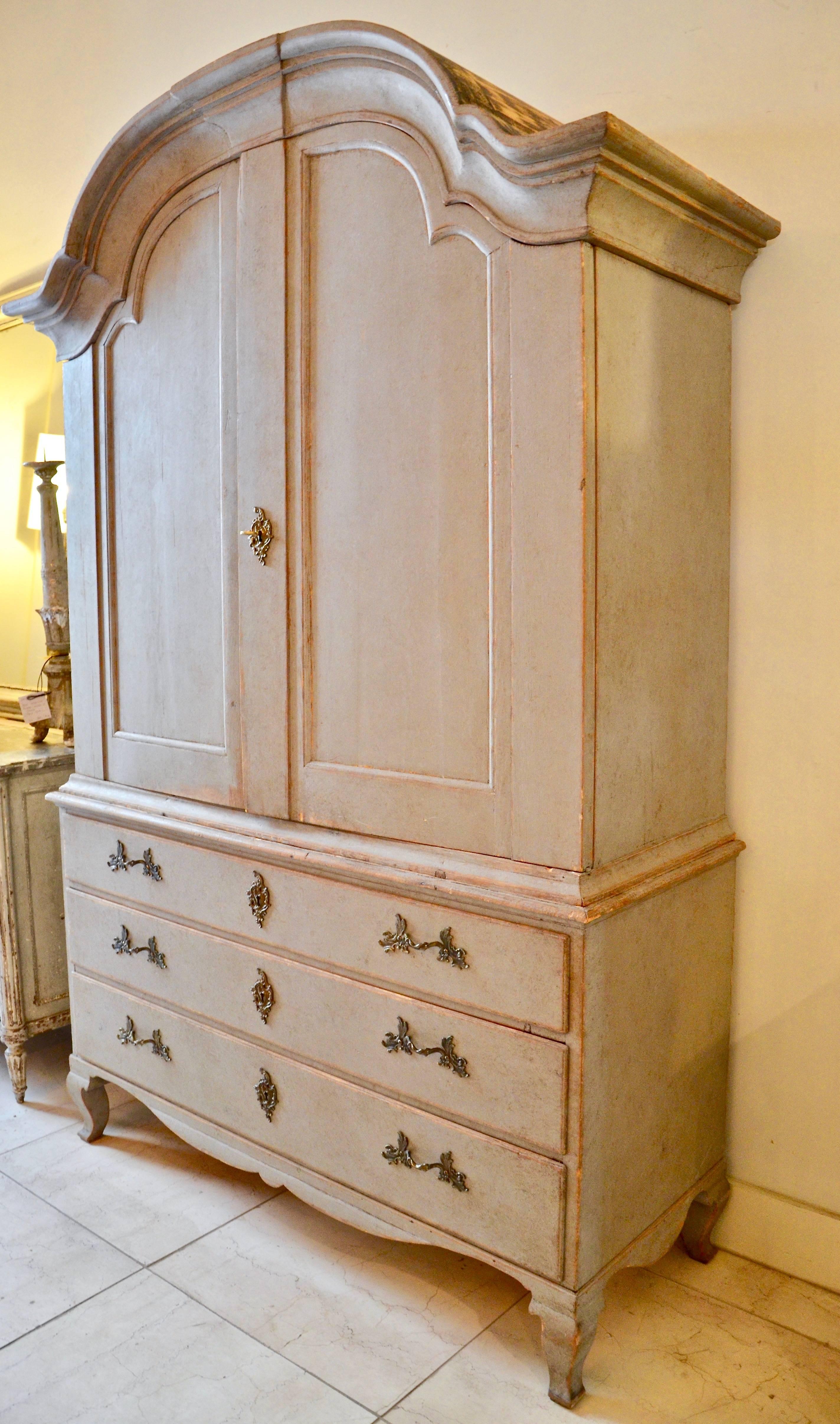 18th century period Swedish rococo cabinet in two parts with bonnet top, raised panel doors, three shelves, four small drawers and a notched spoon shelf, supported by sturdy three drawer base with a scalloped apron and cabriole legs.
More than