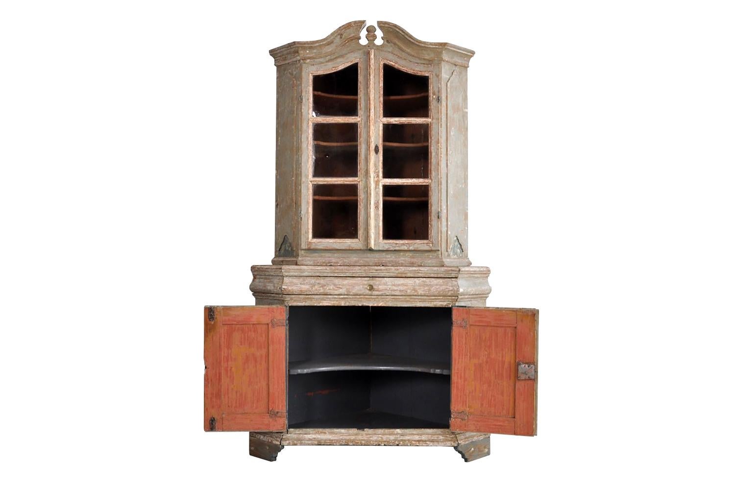 This Swedish 18th century corner cabinet features fine carved detailing and is dry scraped to original paint. A fine example of quality period Swedish furniture making, this cabinet has four front doors in two pairs, the upper doors have glass