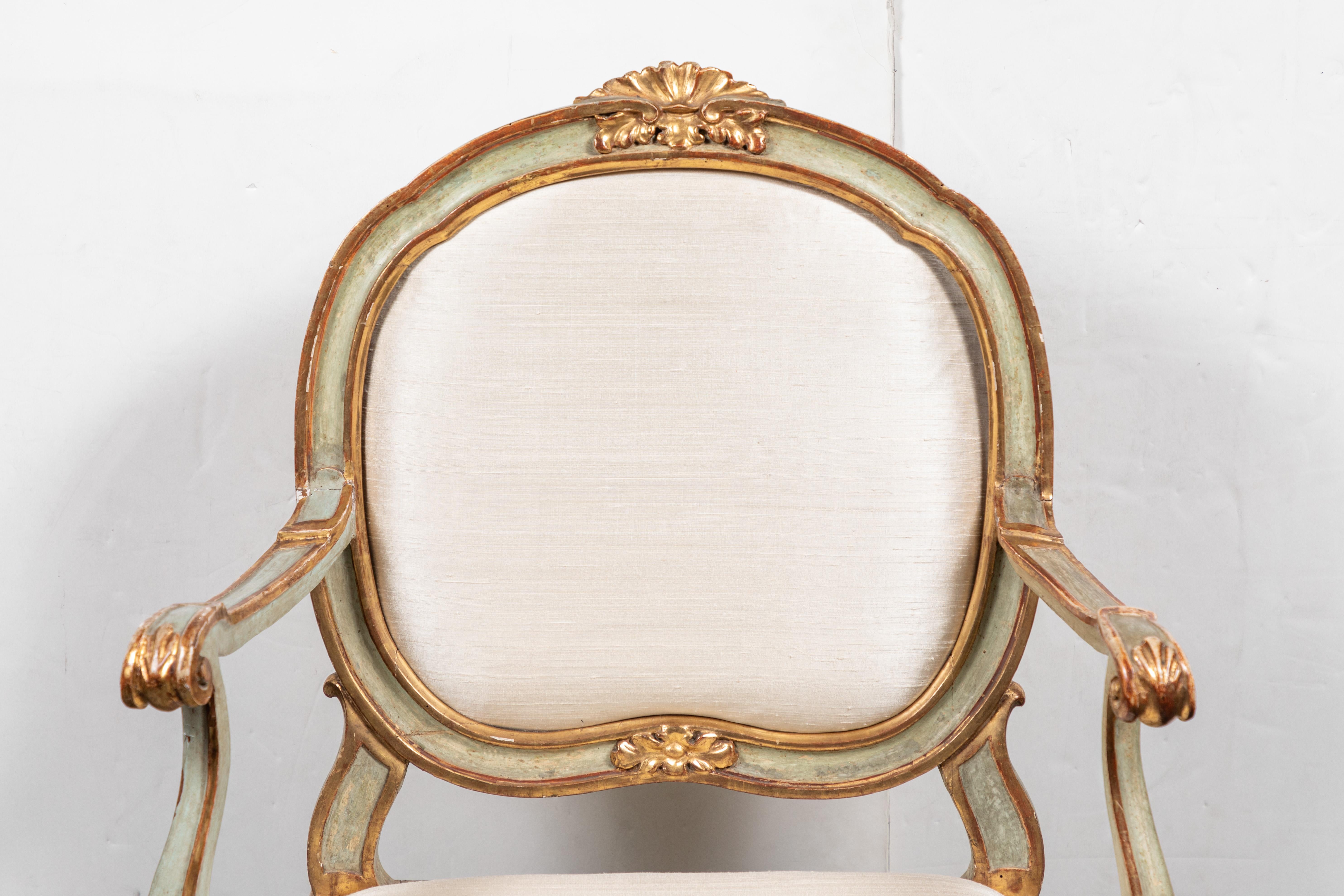 Hand carved, painted, gessoed and 22-karat gold gilded, Venetian armchair. The whole on cabriole legs, and featuring foliate, and shell-form relief carvings throughout. Upholstered in a contemporary, creme, silk.