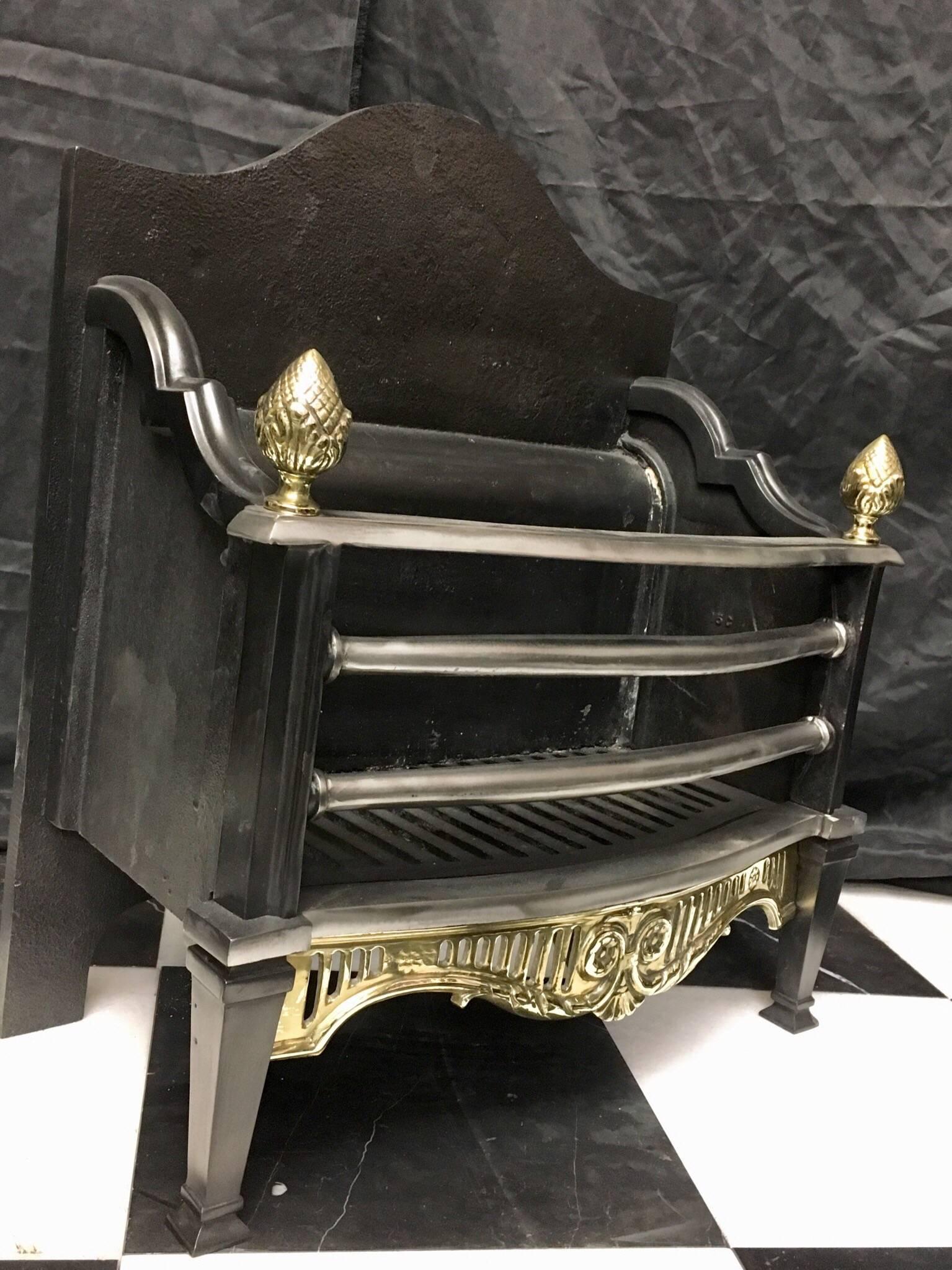 A petite and graceful period Victorian style cast iron and brass fire basket -grate, a shaped cast Iron back plate, with its original fire brick interior and three barred polished grate with stylized brass acorn finials, square standards below on
