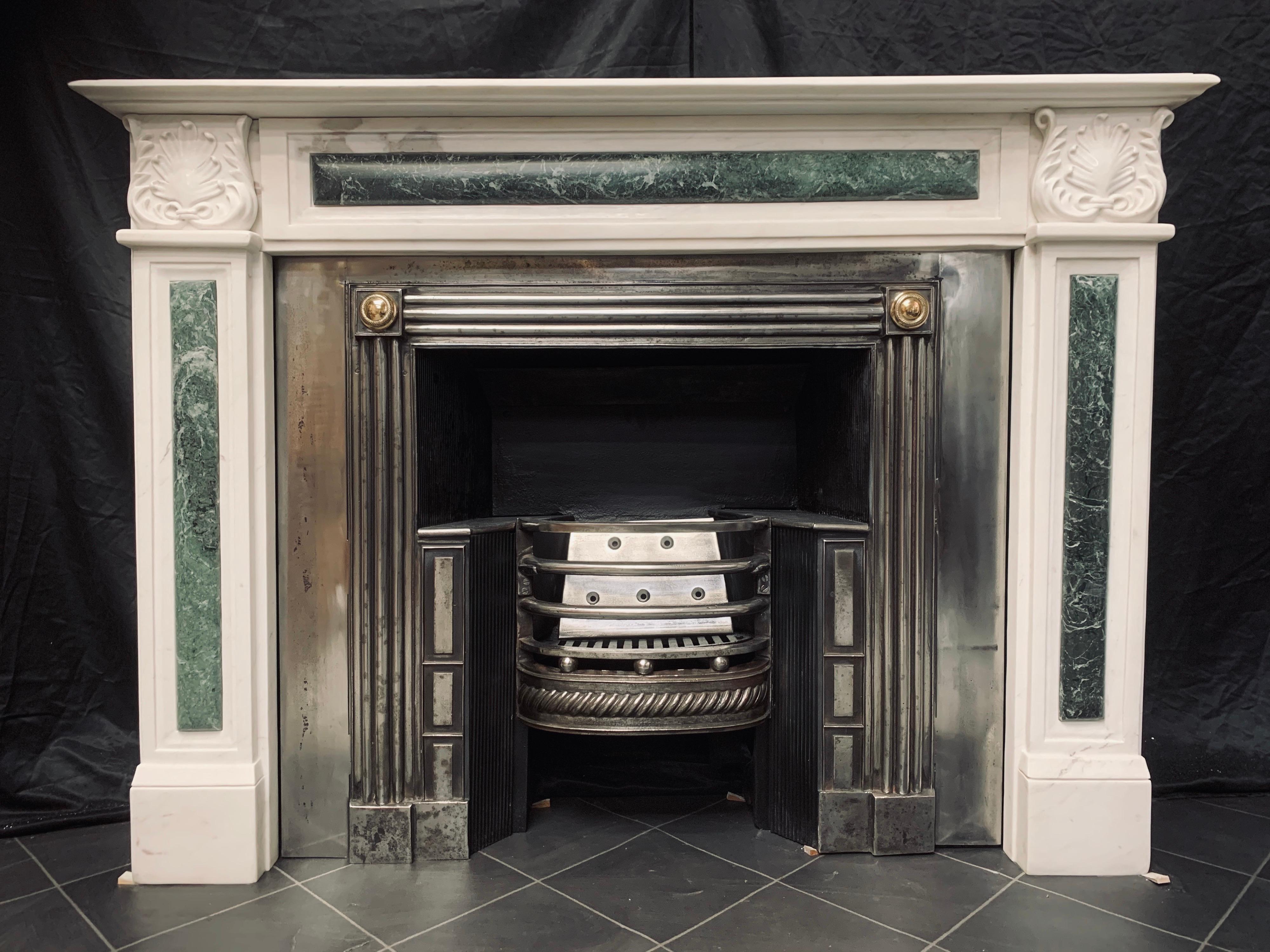 A splendid Period 19th century white statuary marble fireplace surround in the Regency Greek Revival manner. A generous moulded shelf rests above a recessed frieze with a horizontal Verde Antico lozenge, flanked by recessed jambs and further