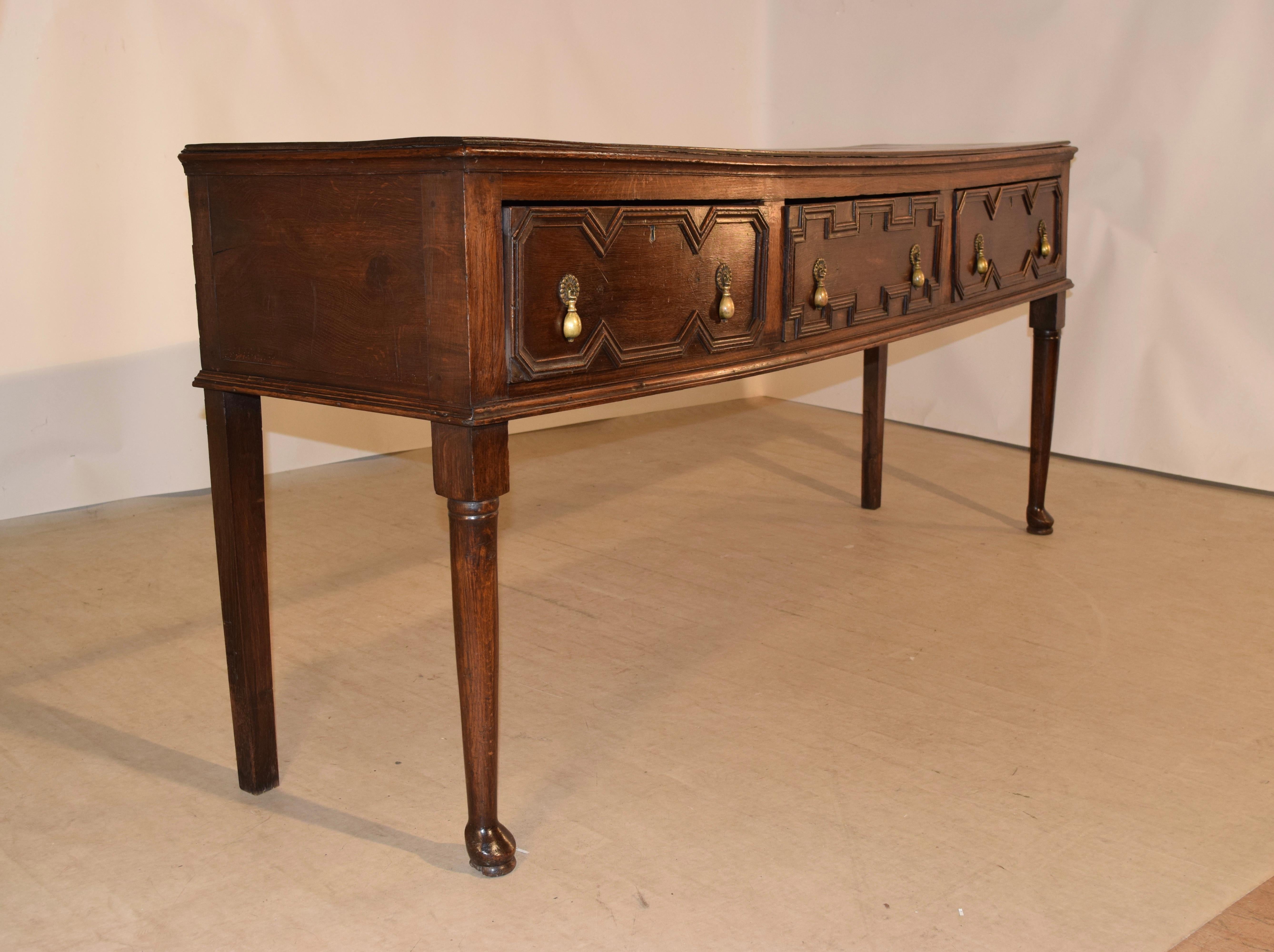 Late 17th-early 18th century English oak sideboard with a swayed top from age and use. The top has a beveled edge and follows down to simple sides and a case with three drawers in the front, all decorated with hand applied geometric moldings and