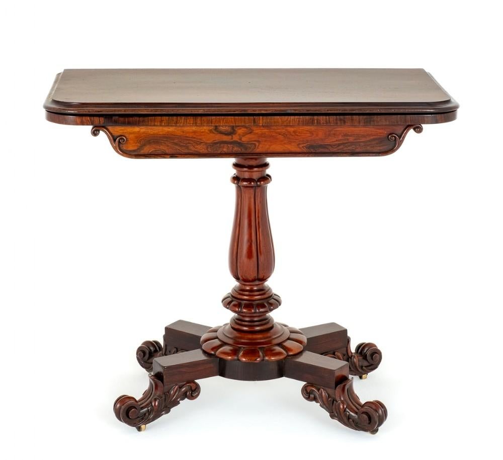 William IV rosewood card table.
This rather impressive card table stands upon a cross section base with boldly carved feet and a carved and turned socle. The column also being of a turned and carved form. The top of the table featuring Rio rosewood