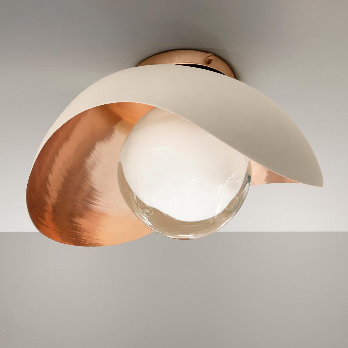 The Perla flushmount features an organic brass shell nestling our Sfera glass handblown in Tuscany. The first images show the fixture with a polished copper interior and sand white exterior finish-subsequent pictures show it in a selection of
