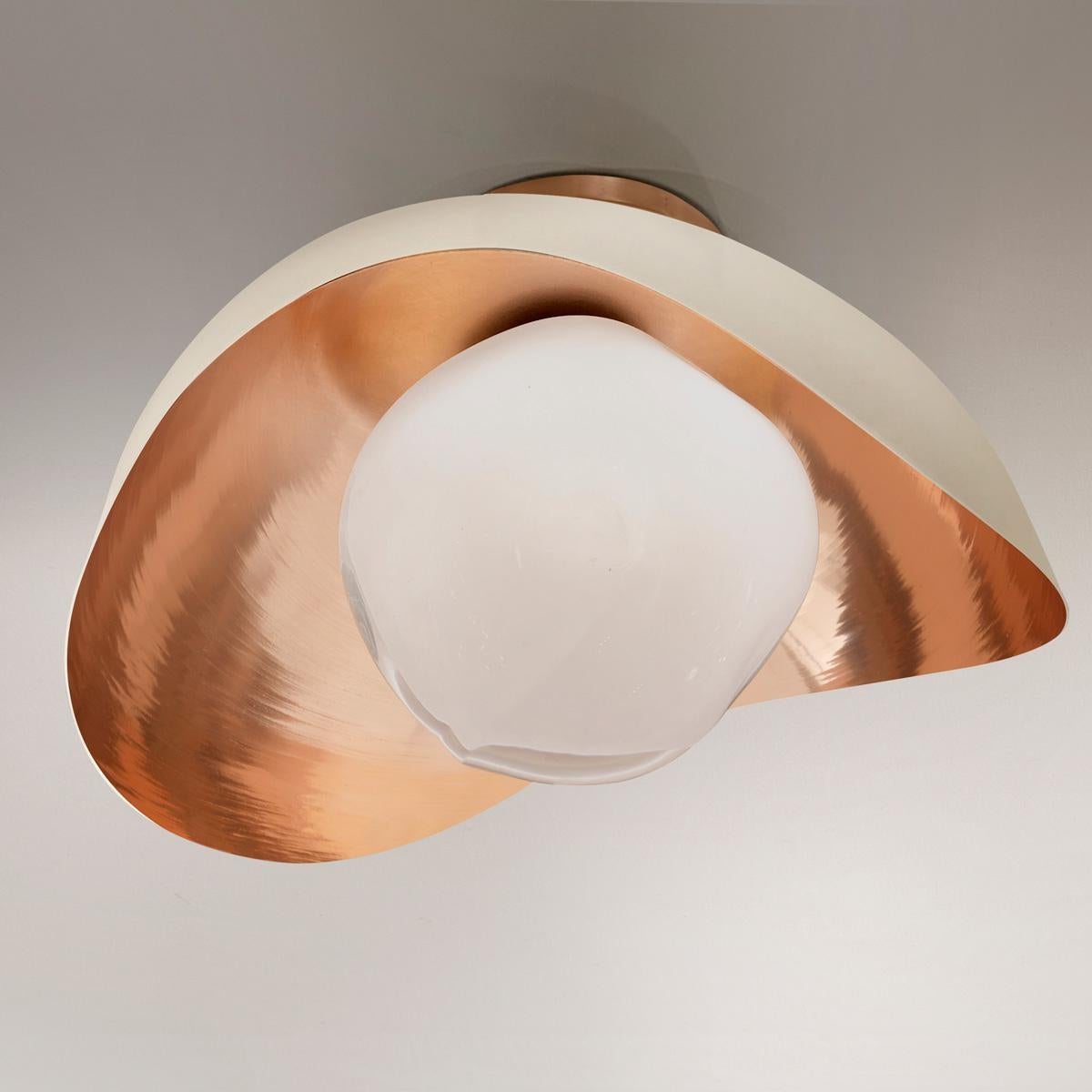 The Perla flushmount features an organic brass shell nestling our Sfera glass handblown in Tuscany. The first images show the fixture with a polished copper interior and sand white exterior finish-subsequent pictures show it in a selection of