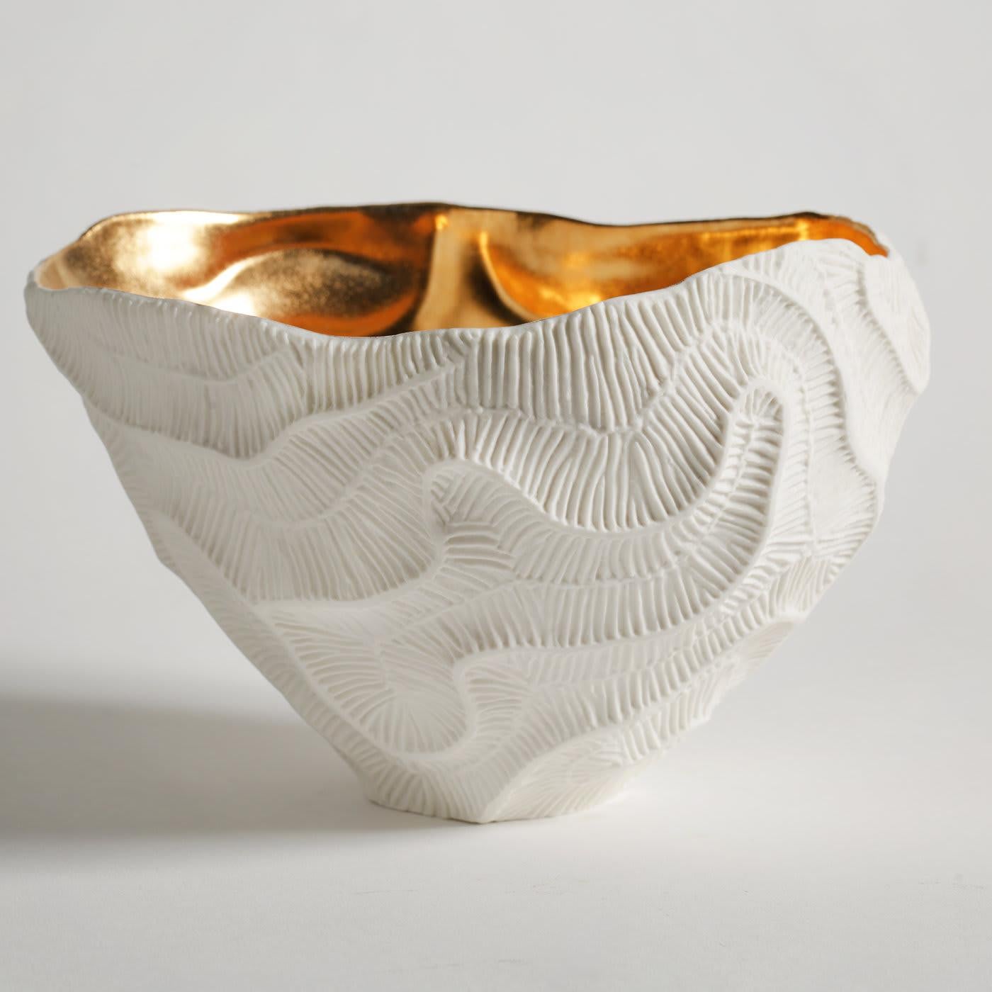 Fossils of madrepore inspire the minute texture decorating the exterior of this striking bowl of the Fossilia collection. A meticulously crafted mold and the use of unglazed porcelain, or 