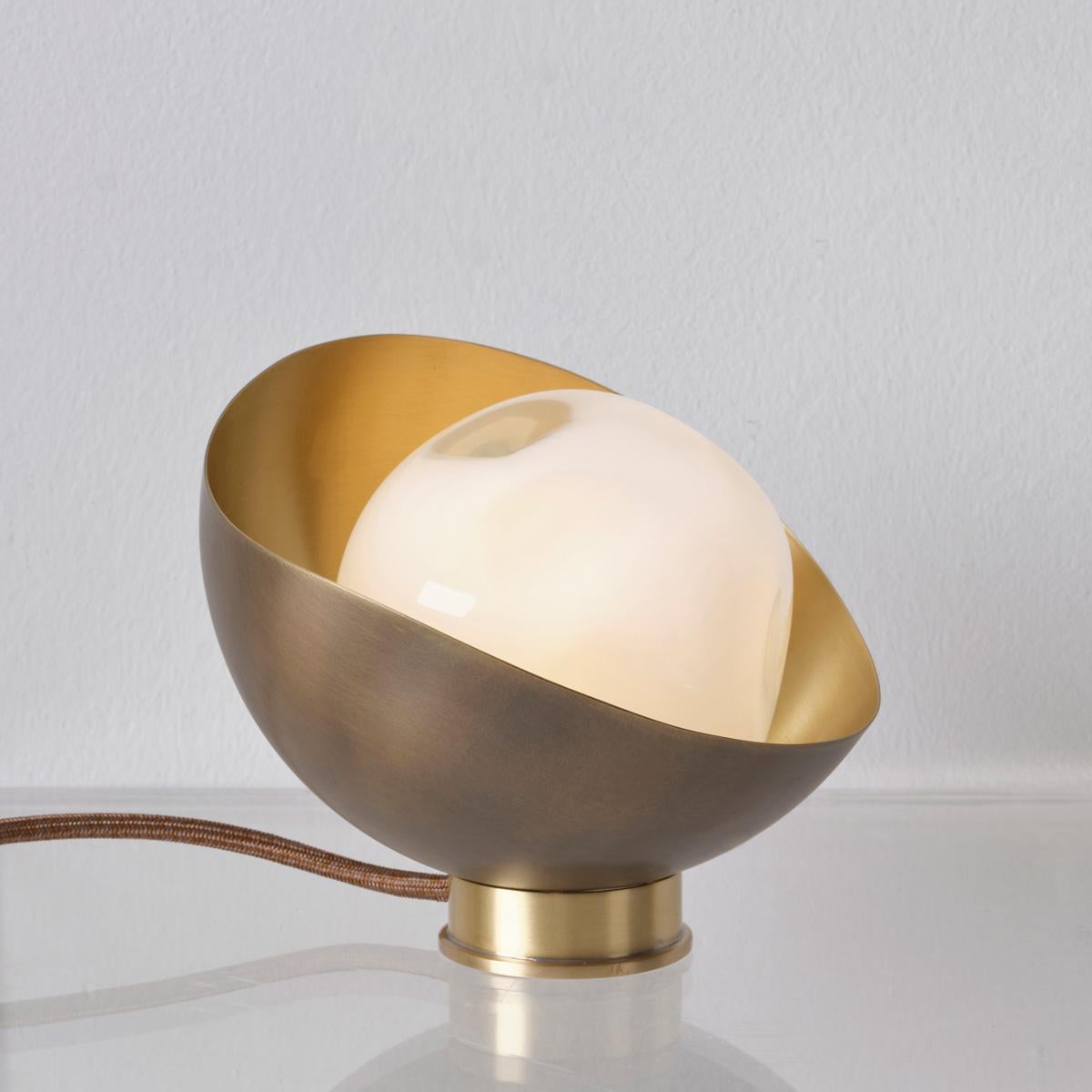 La lampe de table Perla Mini est la plus petite de la collection Perla. Elle est composée d'une coquille organique en laiton dans laquelle est niché notre verre Sfera soufflé à la main à Murano. Voir les modèles Perla et Perla Grande pour des