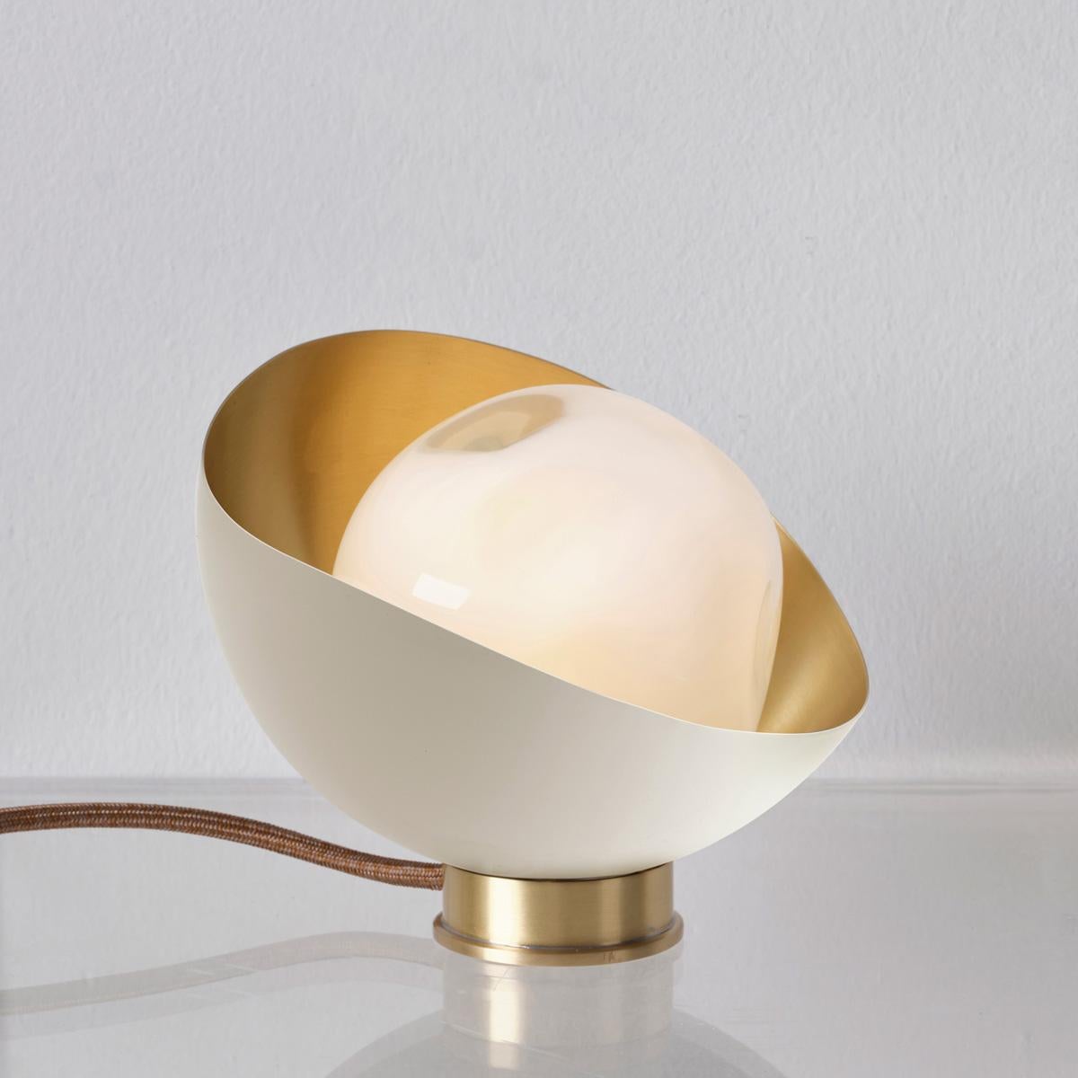La lampe de table Perla Mini est la plus petite de la collection Perla. Elle est composée d'une coquille organique en laiton dans laquelle est niché notre verre Sfera soufflé à la main à Murano. Voir les modèles Perla et Perla Grande pour des