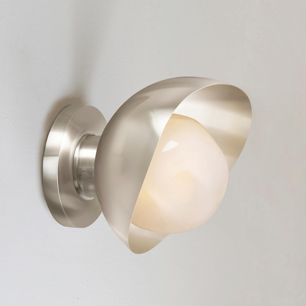 The Perla Mini wall light is the smallest member of the Perla collection featuring an organic brass shell nestling our Sfera glass handblown in Murano. See the Perla and Perla Grande for larger models.

The primary images show it in polished/satin