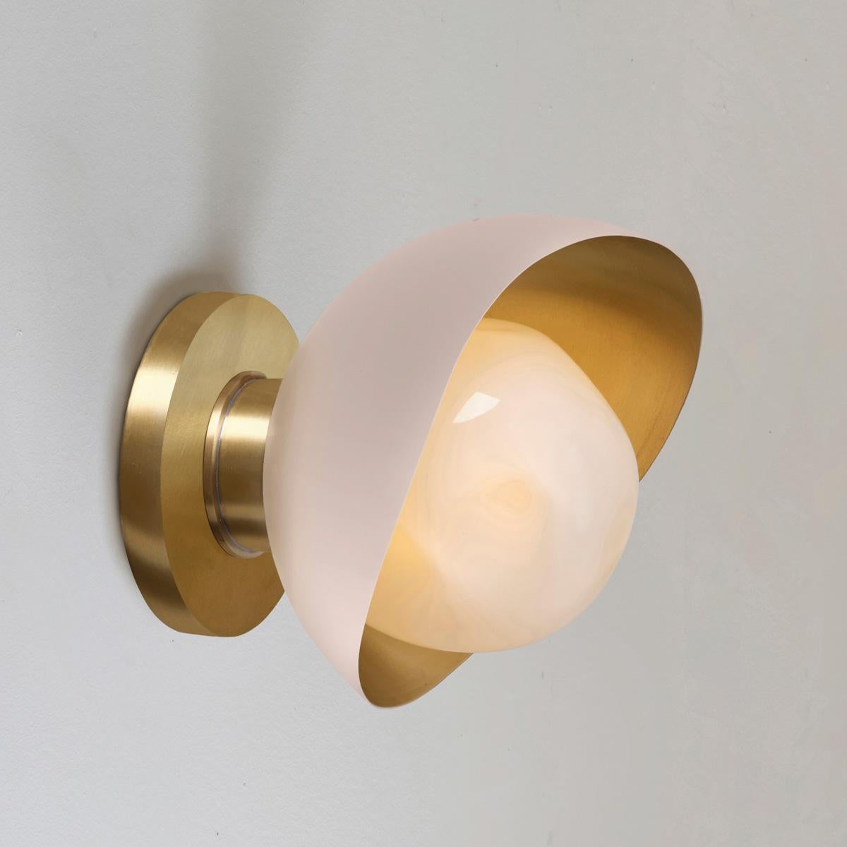 The Perla Mini wall light is the smallest member of the Perla collection featuring an organic brass shell nestling our Sfera glass handblown in Murano. See the Perla and Perla Grande for larger models.

The primary images show it in Powder Pink and