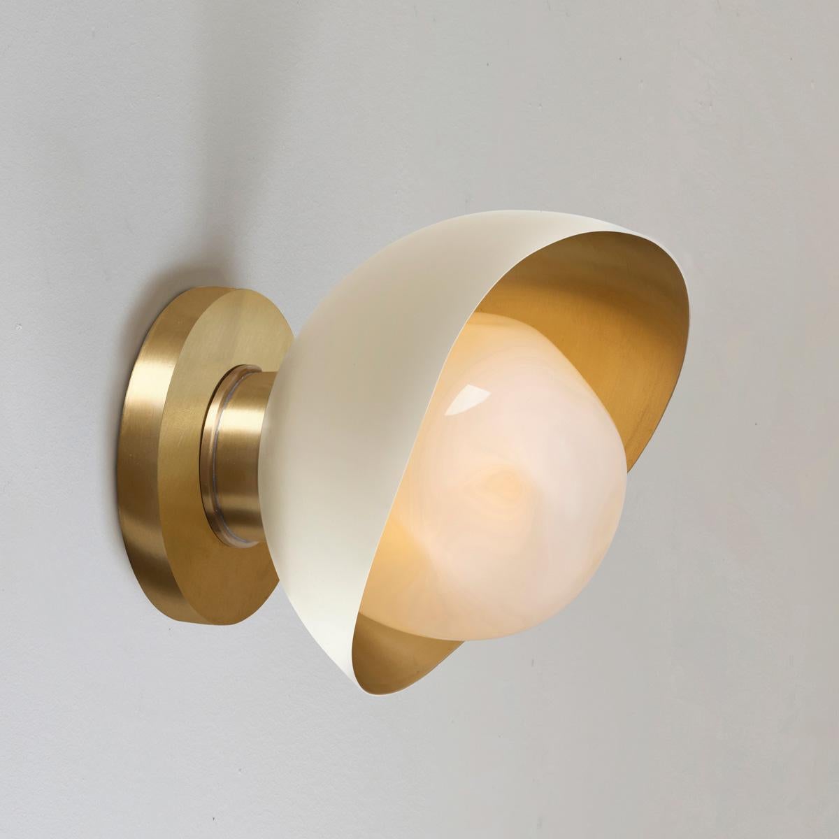 The Perla Mini wall light is the smallest member of the Perla collection featuring an organic brass shell nestling our Sfera glass handblown in Murano. See the Perla and Perla Grande for larger models.

The primary images show it in Sand White and