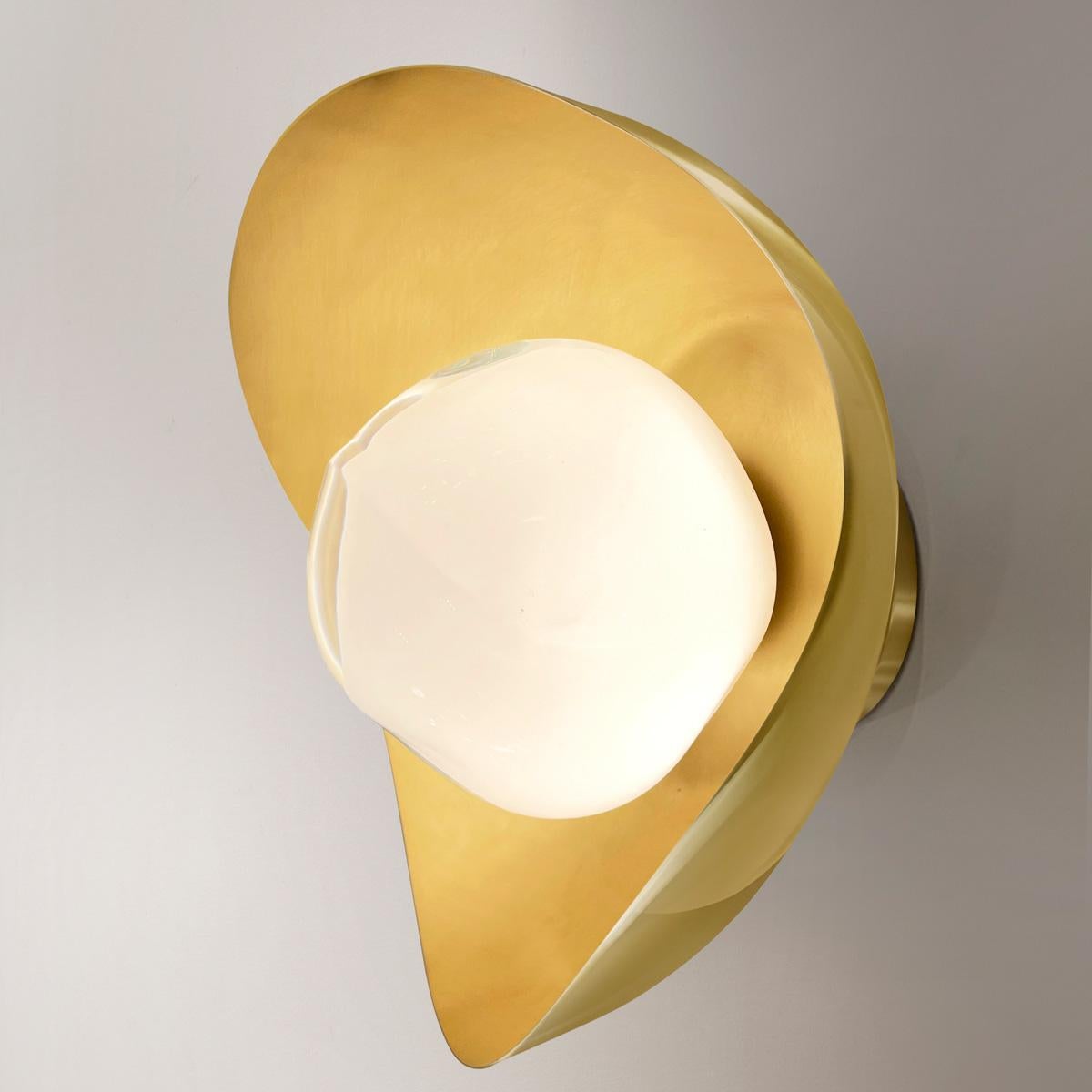 The Perla wall light features an organic brass shell nestling our Sfera glass handblown in Tuscany. The first images show the fixture with a satin brass interior and polished brass exterior finish-subsequent pictures show it in a selection of