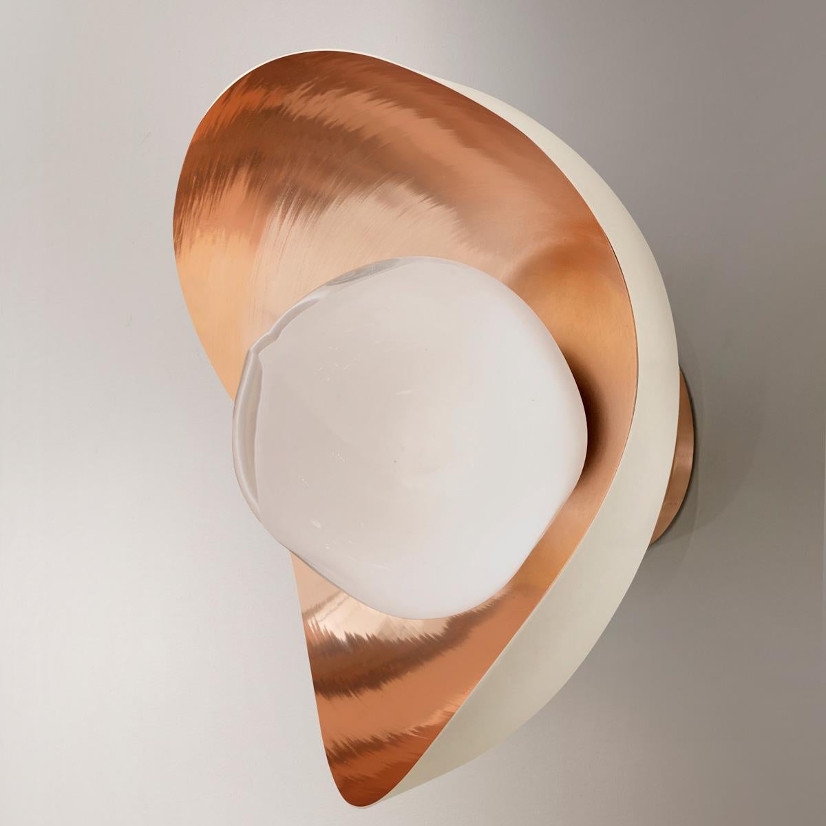 The Perla wall light features an organic brass shell nestling our Sfera glass handblown in Tuscany. The first images show the fixture with a polished copper interior and sand white exterior finish-subsequent pictures show it in a selection of