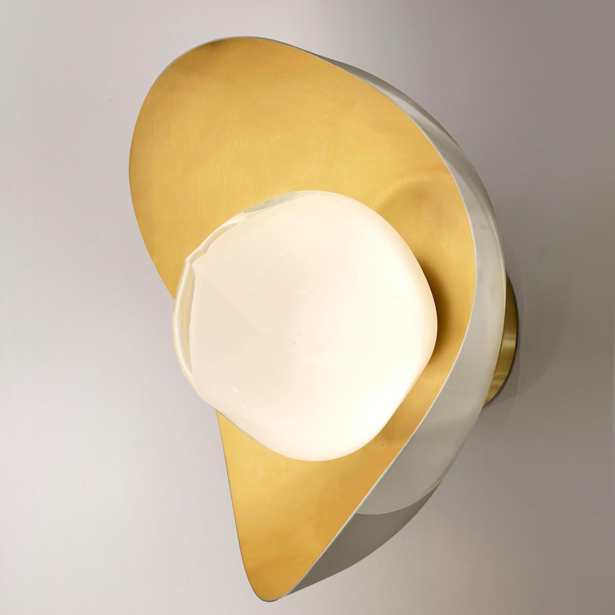 The Perla wall light features an organic brass shell nestling our Sfera glass handblown in Tuscany. The first images show the fixture with a satin brass interior and polished nickel exterior finish-subsequent pictures show it in a selection of