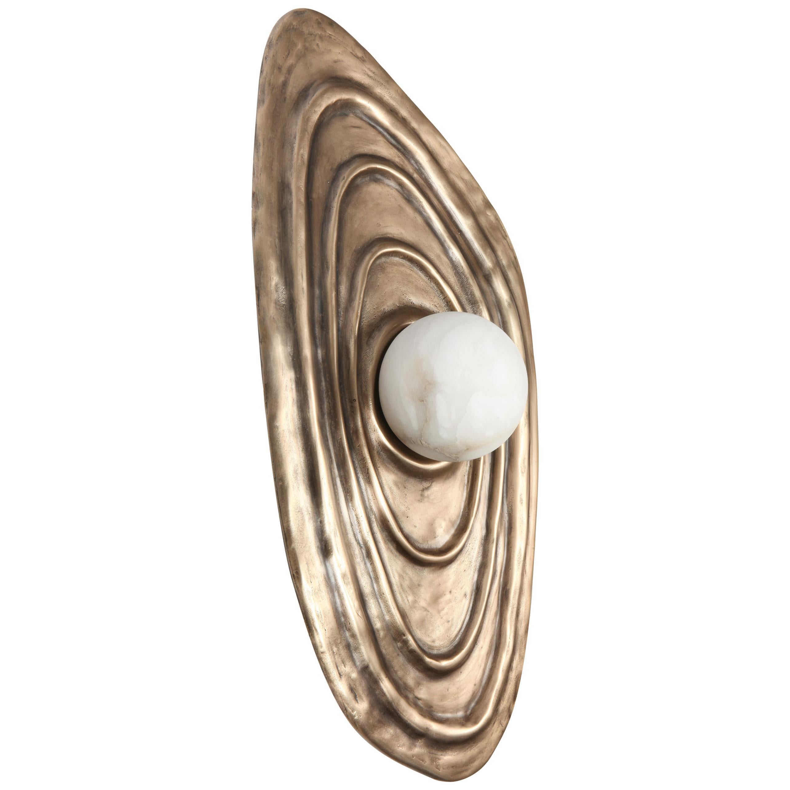 Designed and created by Charles Burnand Studio, the organic shape of the perla wall sconce was inspired by the lines of Japanese gardens with the subtle undulations of the interior of a shell. Cast in bronze the Perla wall sconce can be patinated to