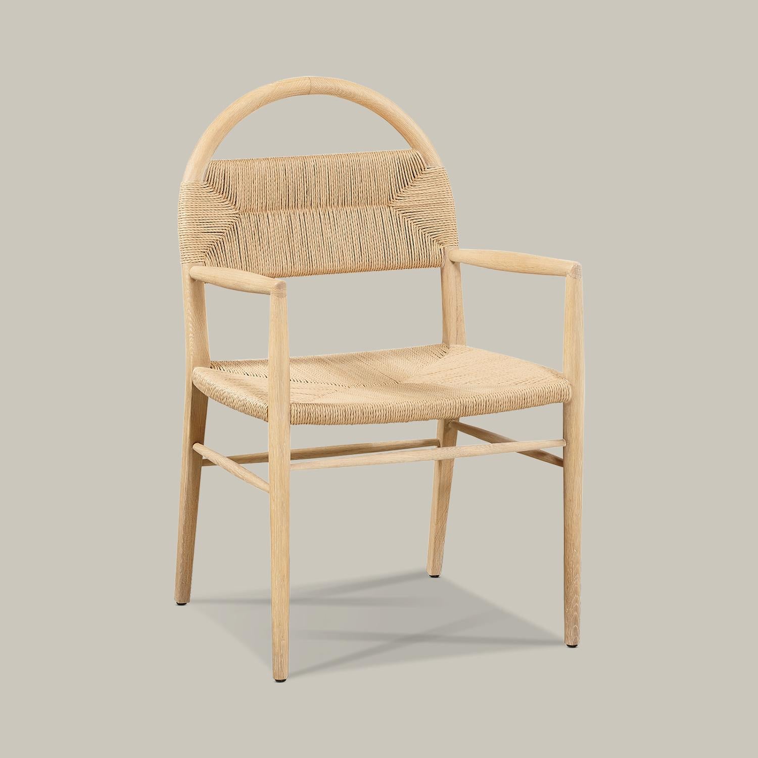 A solid wood arched frame threads through a woven rush seat with arms and backrest to form this well-proportioned, minimalist chair for dining, desk, vanity or an accent in any room. Handmade in Vietnam, this piece is available in cerused European
