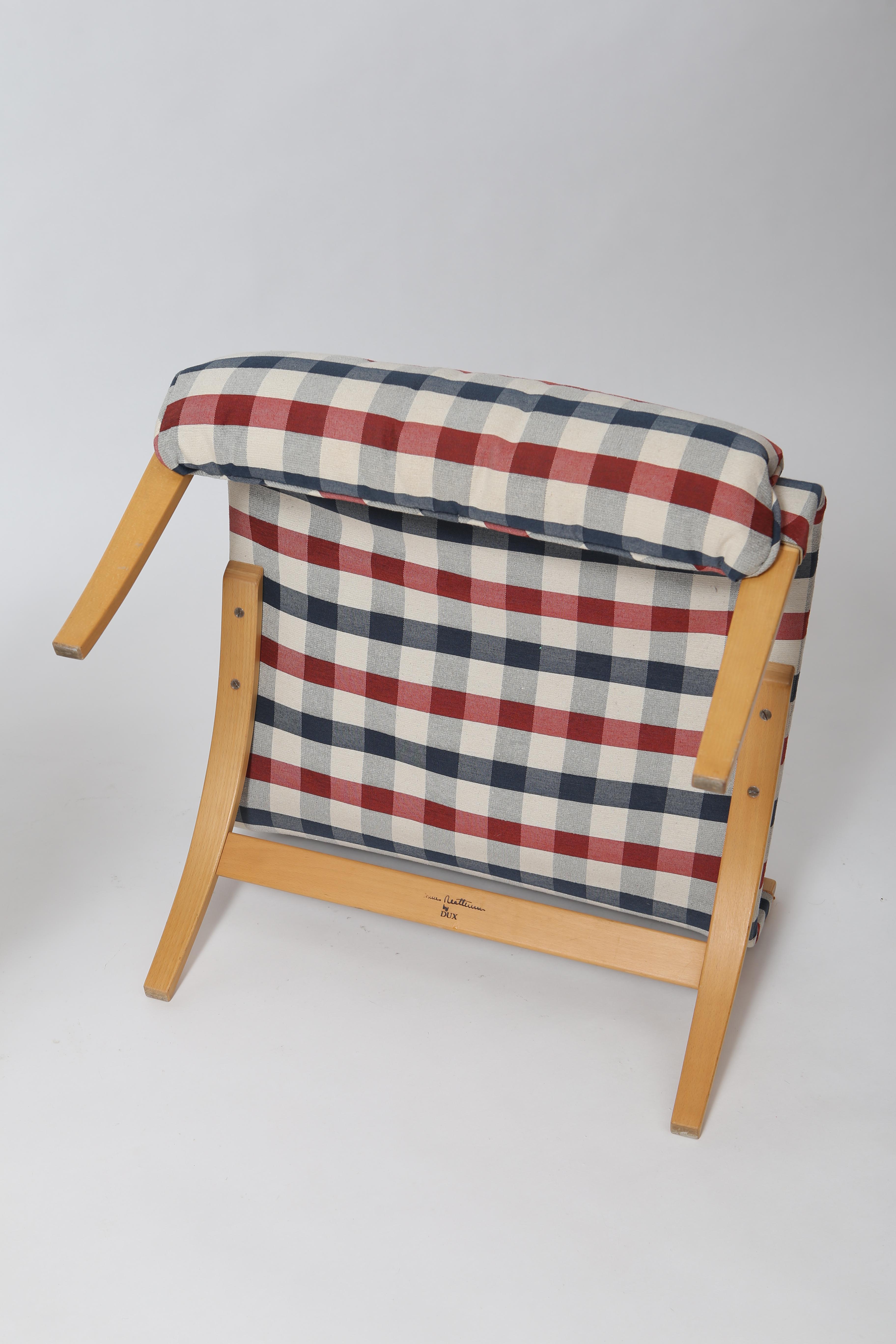 Iconic Pernilla lounge chair with ottoman by Bruno Mathsson. Model 69, produced by Dux of Sweden circa 1970. Reupholstered in plaid cotton twill. Ultra comfortable and lightweight. Bent beech ply frame, linen canvas slings and detachable plaid