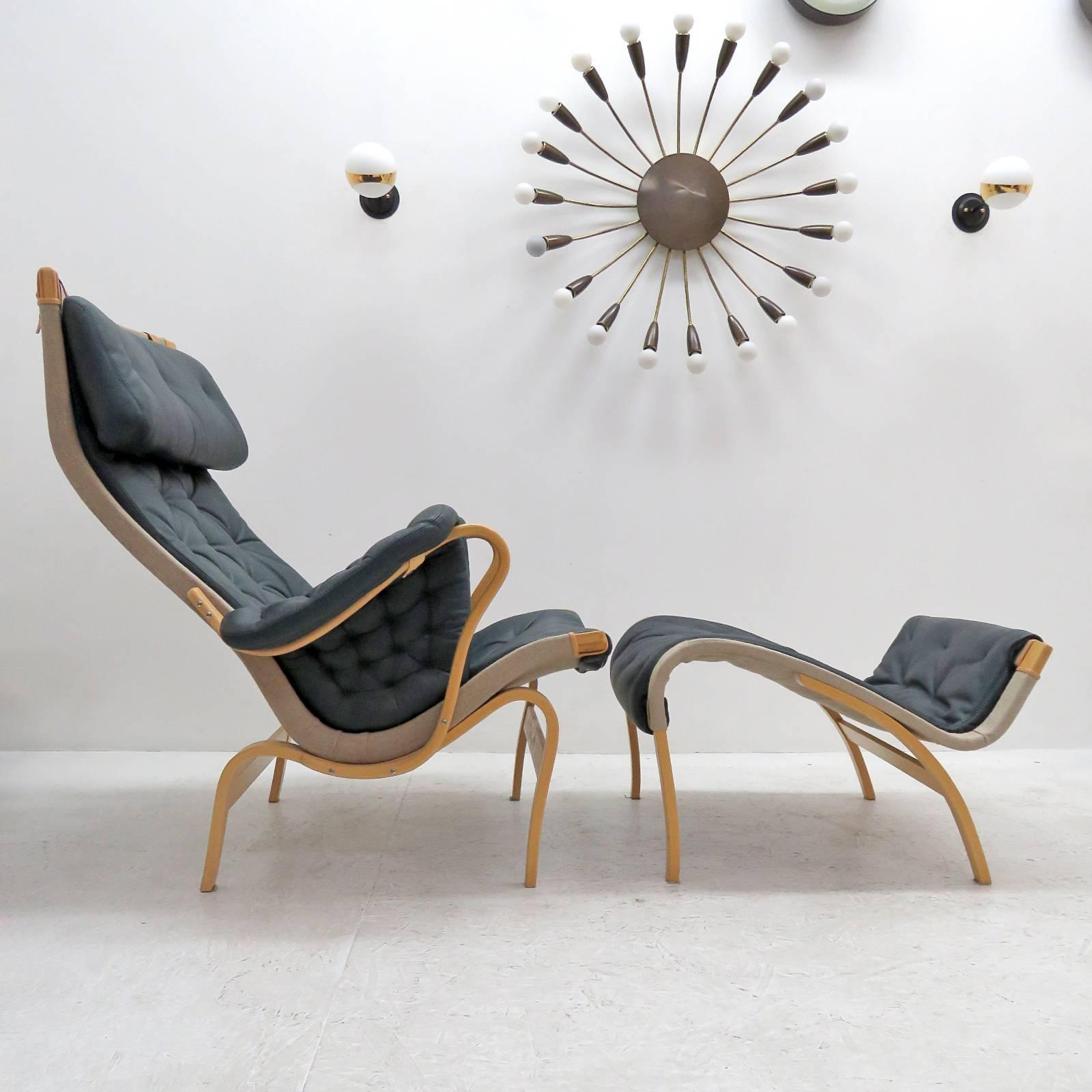 Wonderful early curvilinear lounge chair and ottoman by Bruno Mathsson for DUX, composed of a tufted dark forest green leather cover on canvas, supported by a molded beech plywood frame, with adjustable leather headrest on leather straps, stamped,