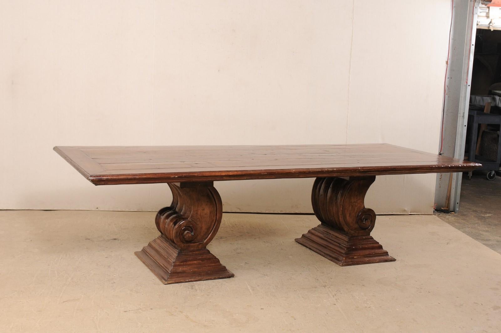 A vintage Brazilian dining room or conference table made of reclaimed peroba wood. This 9.5 foot long table from Brazil features a rectangular-shaped top, raised upon a pair of fabulous volute scrolled pedestal bases. Each of the bases (or legs) are