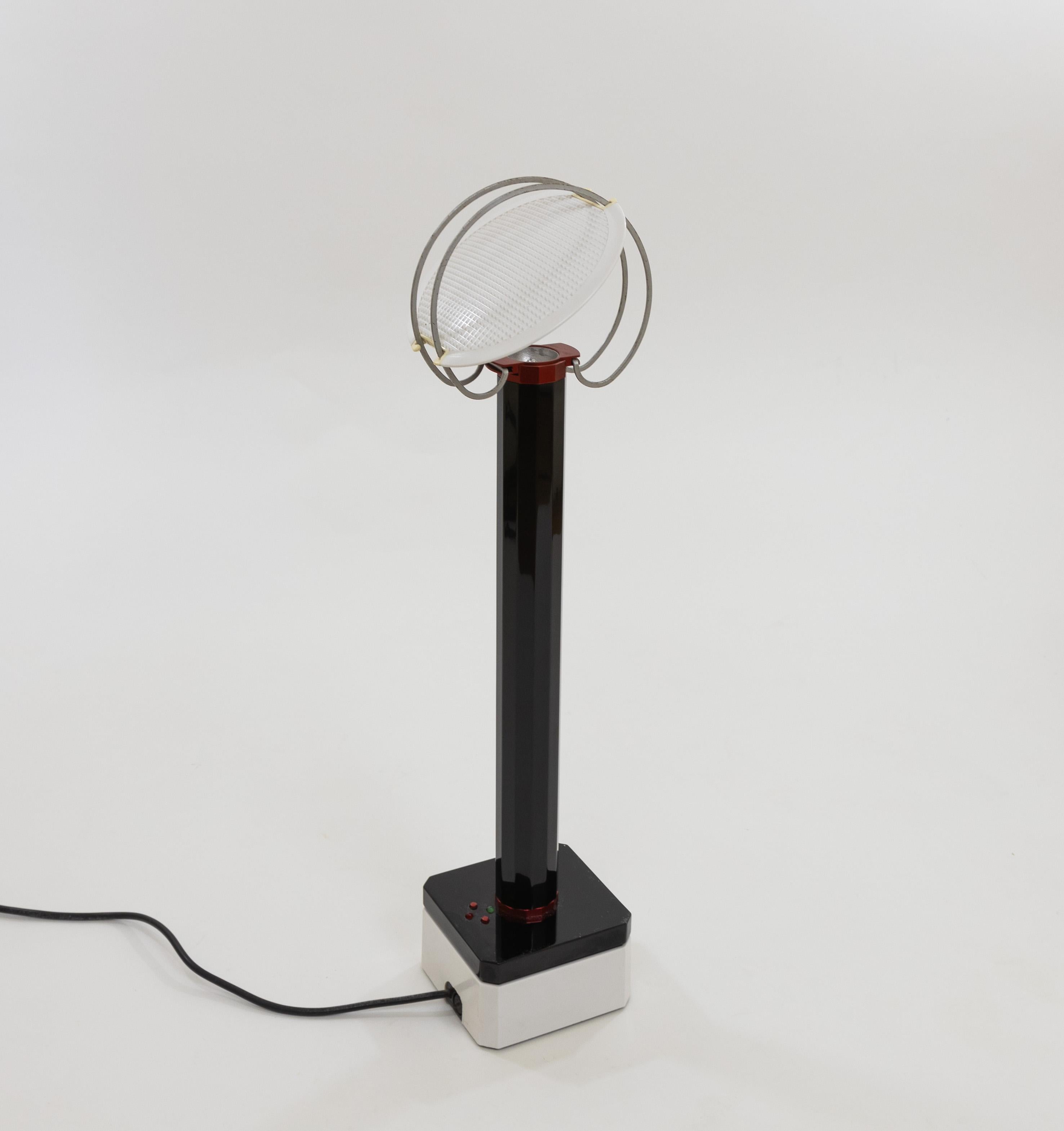 Lámpara de sobremesa Perpetua, diseñada por Afra & Tobia Scarpa en 1981 y fabricada por Flos.

Esta lámpara halógena consta de un tallo de aluminio negro, una pantalla redonda de metal y una base de plástico blanco que sirve de cargador. El