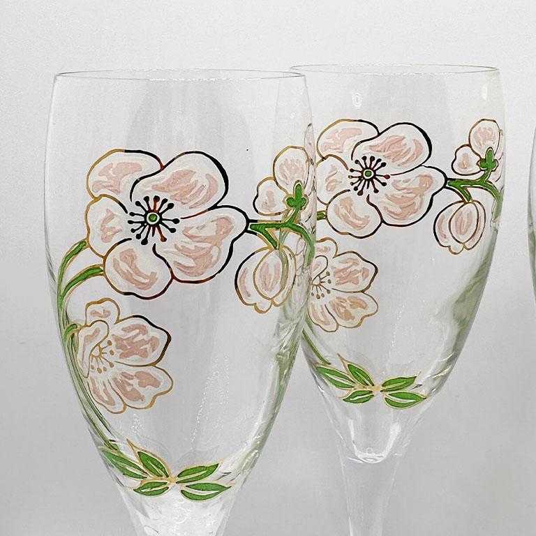 A set of four Perrier-Jouët hand-painted champagne flutes. This set features 4 vintage glasses each hand-painted with a Japanese anemone design of pink, white, and gold. The original artist, Emile Gallé was commissioned by Octave Gallice in 1902 to