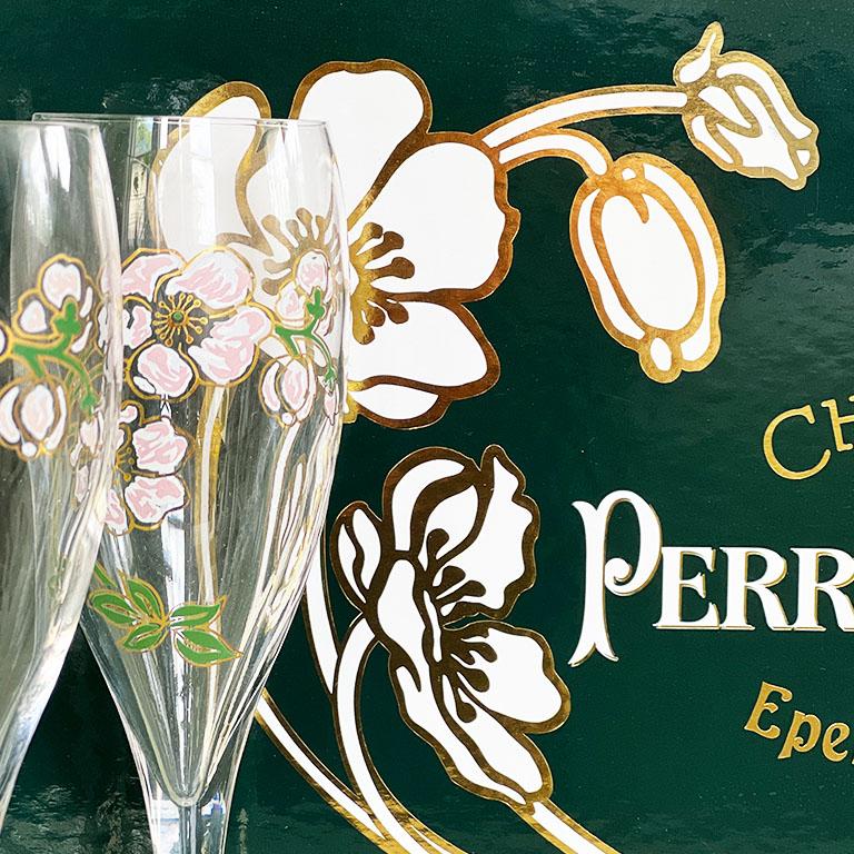 A set of six Perrier-Jouët hand-painted champagne flutes. Never used, and still in the original box, this set features 6 glasses each hand-painted with a Japanese anemone design of pink, white, and gold. The original artist, Emile Gallé was