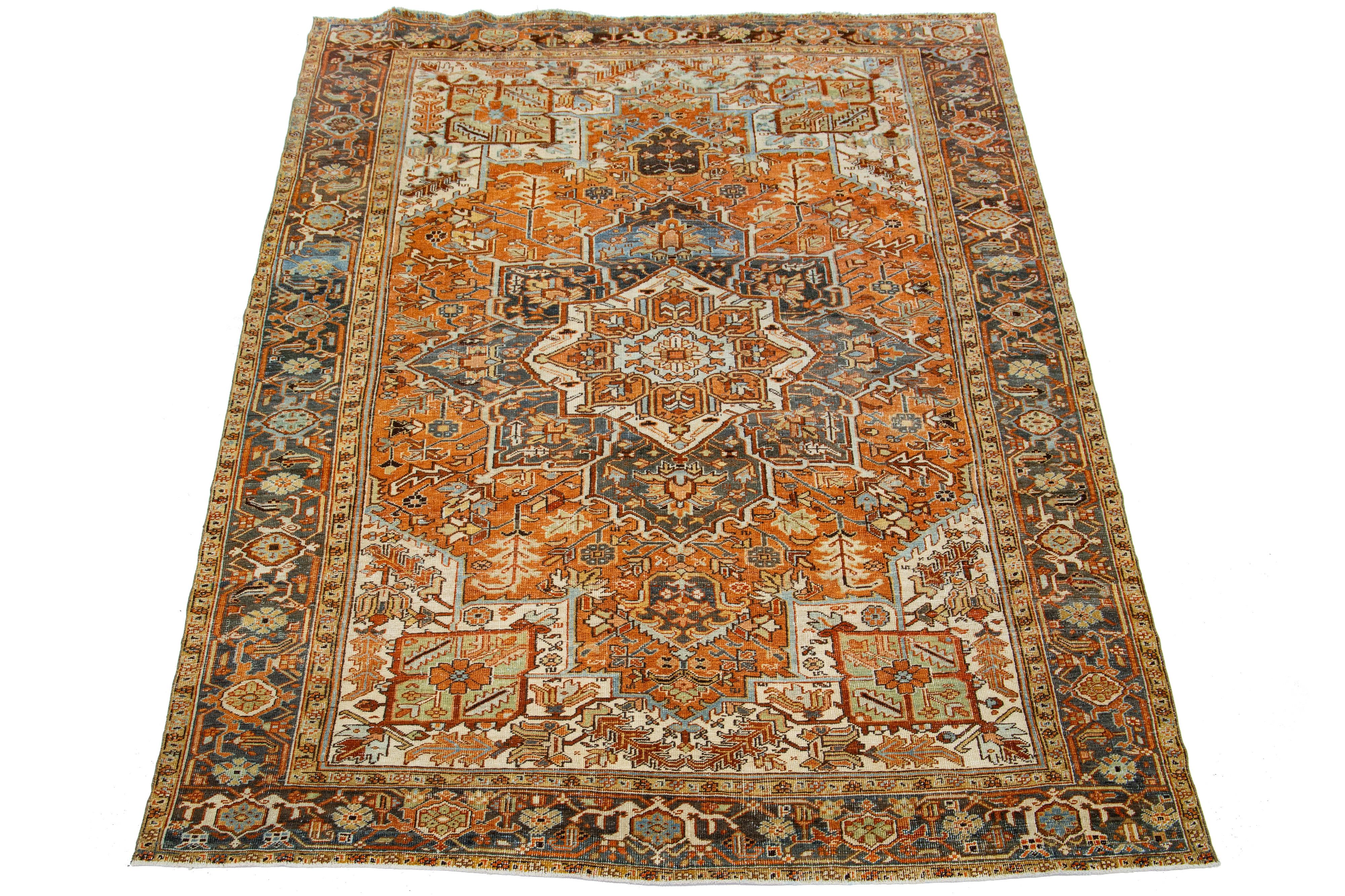 This antique Persian Heriz rug displays its impressive medallion design and hand-knotted wool construction. The orange-rust field is a backdrop for the eye-catching geometric floral pattern, adorned in shades of blue and brown.

This rug measures