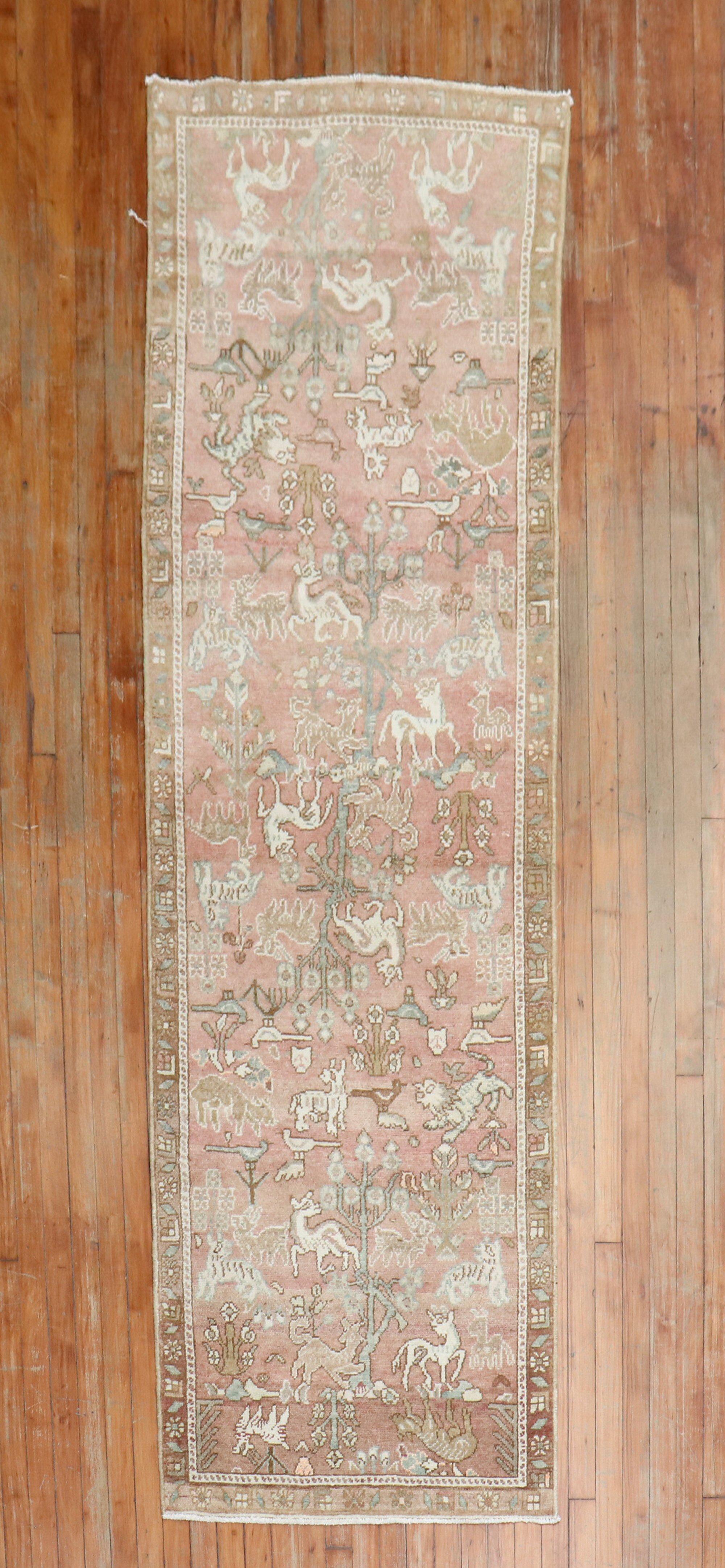 Make a bold statement in a hallway with this mid-20th-century tribal Persian runner featuring a folksy motif on a soft pink field. Various Animals are found within the field. The colors are casual,

circa 1930, measures: 2'9