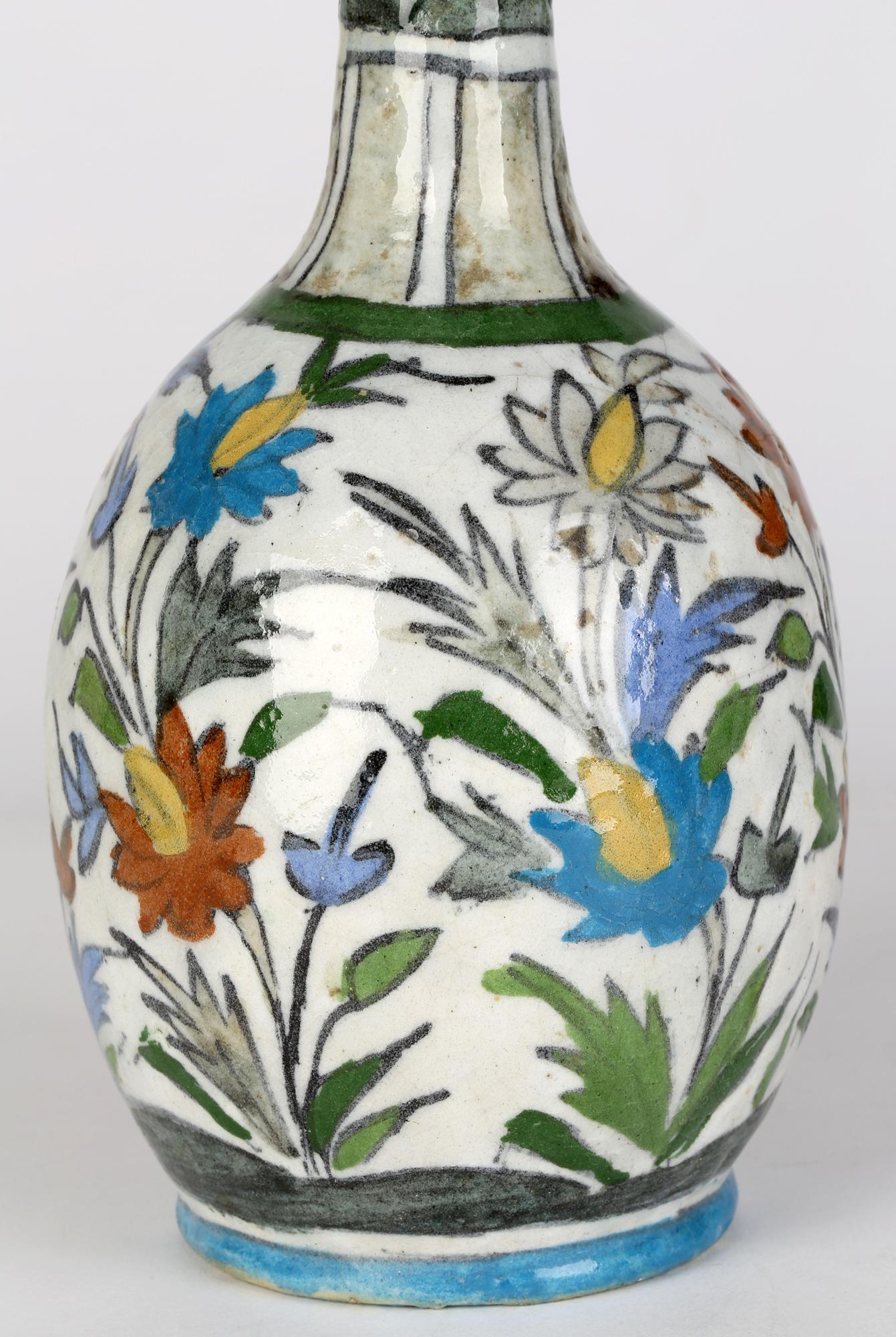 A good antique Persian art pottery bottle shaped vase hand painted with floral designs and dating from the 19th century. The vase stands raised on a round unglazed foot with a recessed base with a lower round bulbous body and tall slender neck with