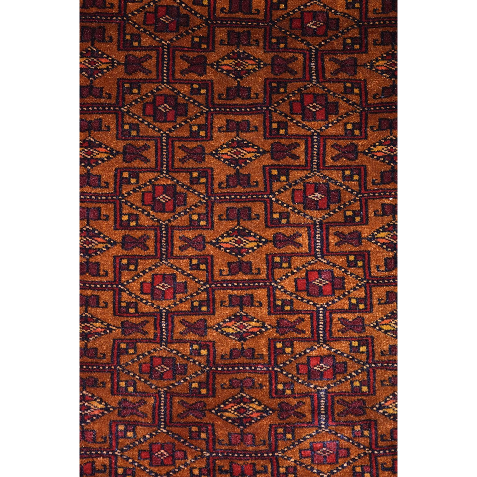 This Persian Balouchi carpet in handspun wool and vegetable dyes circa 1930 exhibits an all-over geometric design in rich golds and reds, with touches of blue and yellow throughout the field and borders. Intricate and sophisticated in its execution,