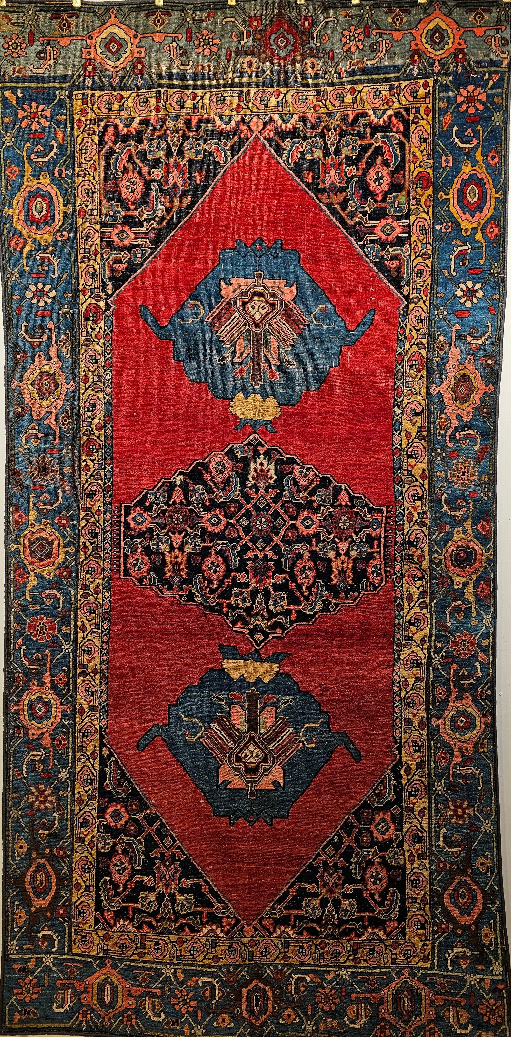 Late 19th century Persian Bidjar in a medallion geometric pattern.  The rug has an open field design set on a rich carnelian  red background with the central medallion in navy blue with a Herati pattern.  A symmetric small medallion with a fantastic