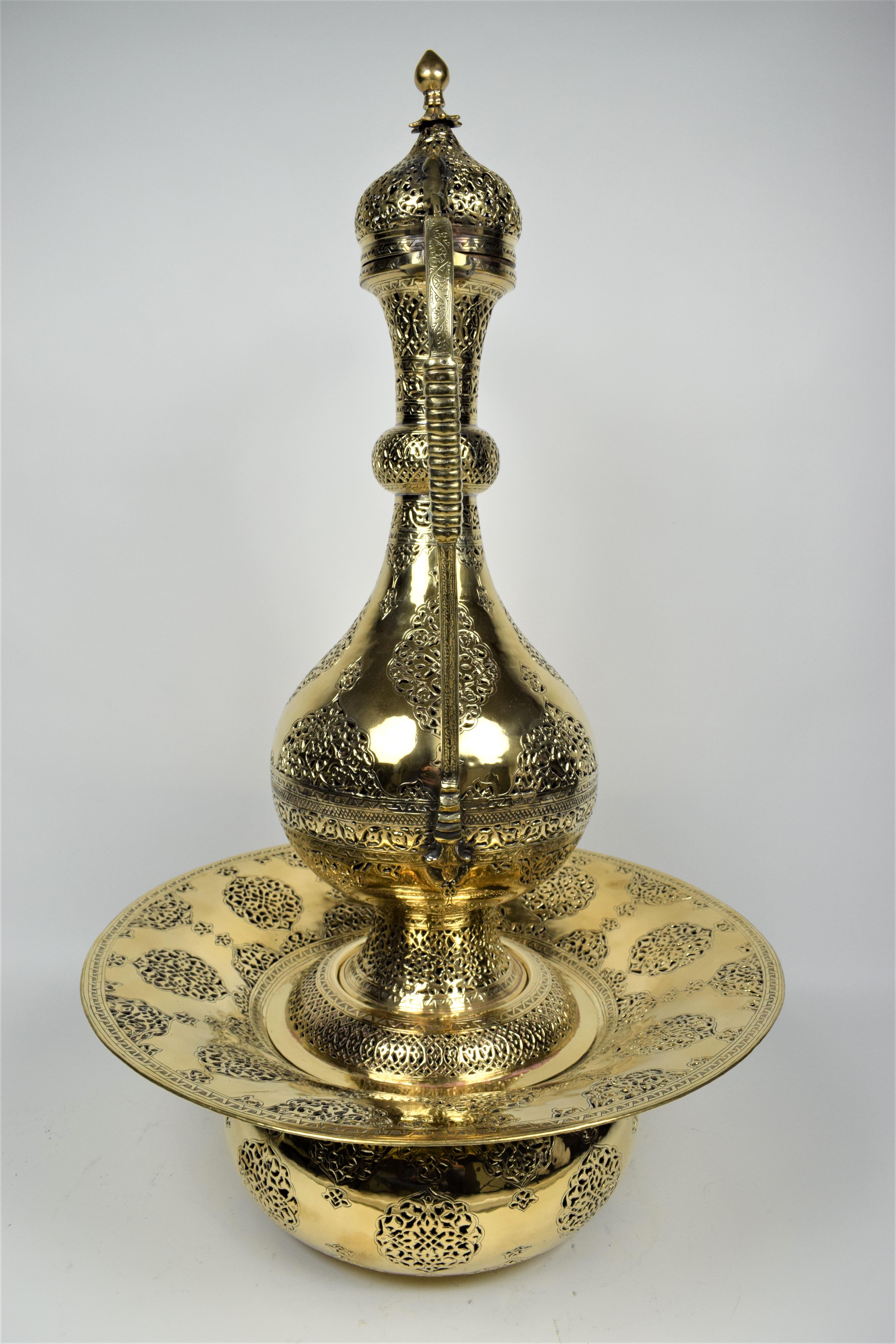 Persian brass cutwork ewer and basin set, early 20th century
An exquisite 3-piece ensemble consisting of a circular basin, cover and Ewer which have been intricately engraved with several bands of decoration in geometrical and vegetal cutwork. The