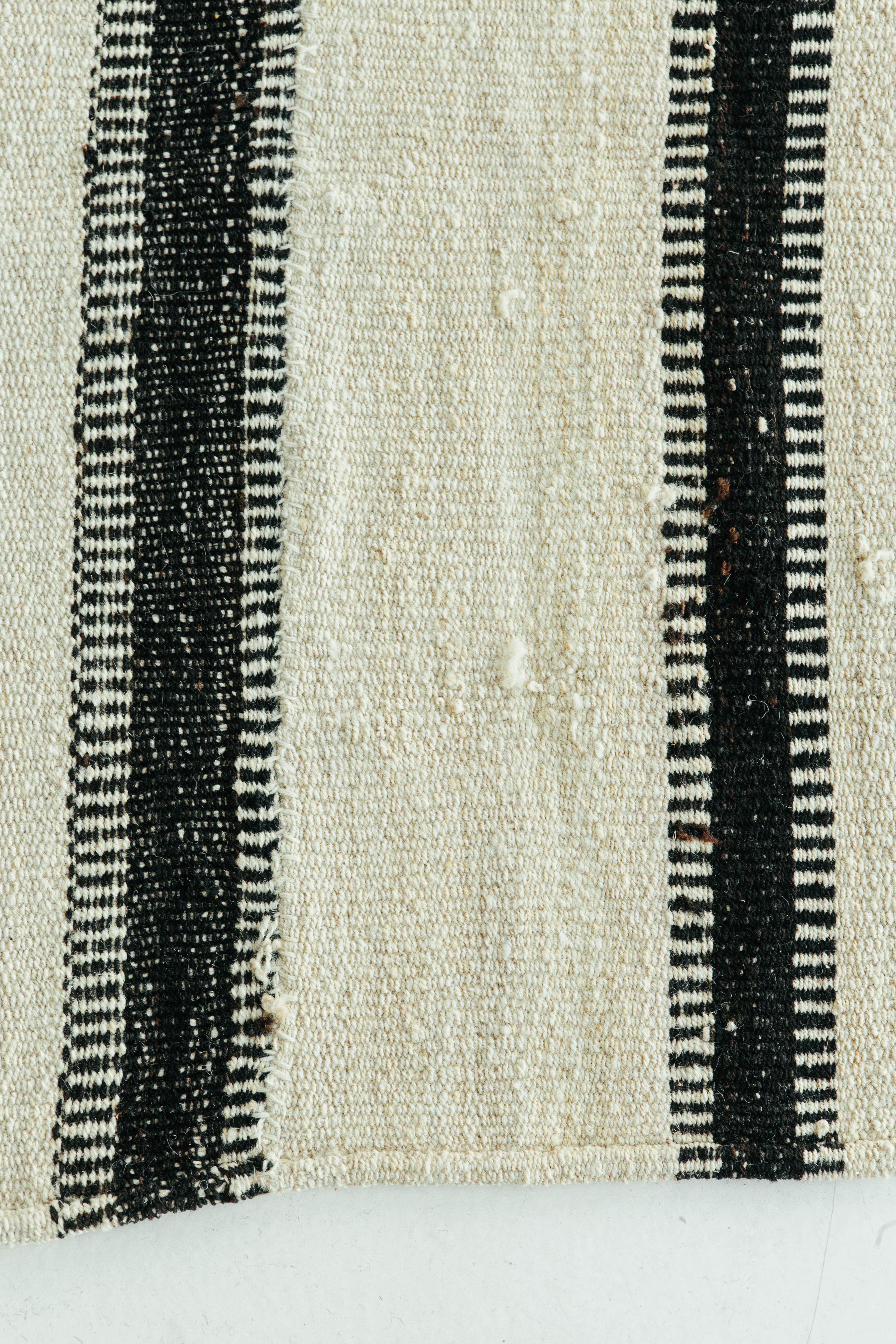 This Persian Jejim Kilim is a banded flat-weave with alternating black and ivory colors. The stripes have a unique toothing pattern that adds even more character. Persian flat weaves are made up of some of the best wool and weaved exceptionally to