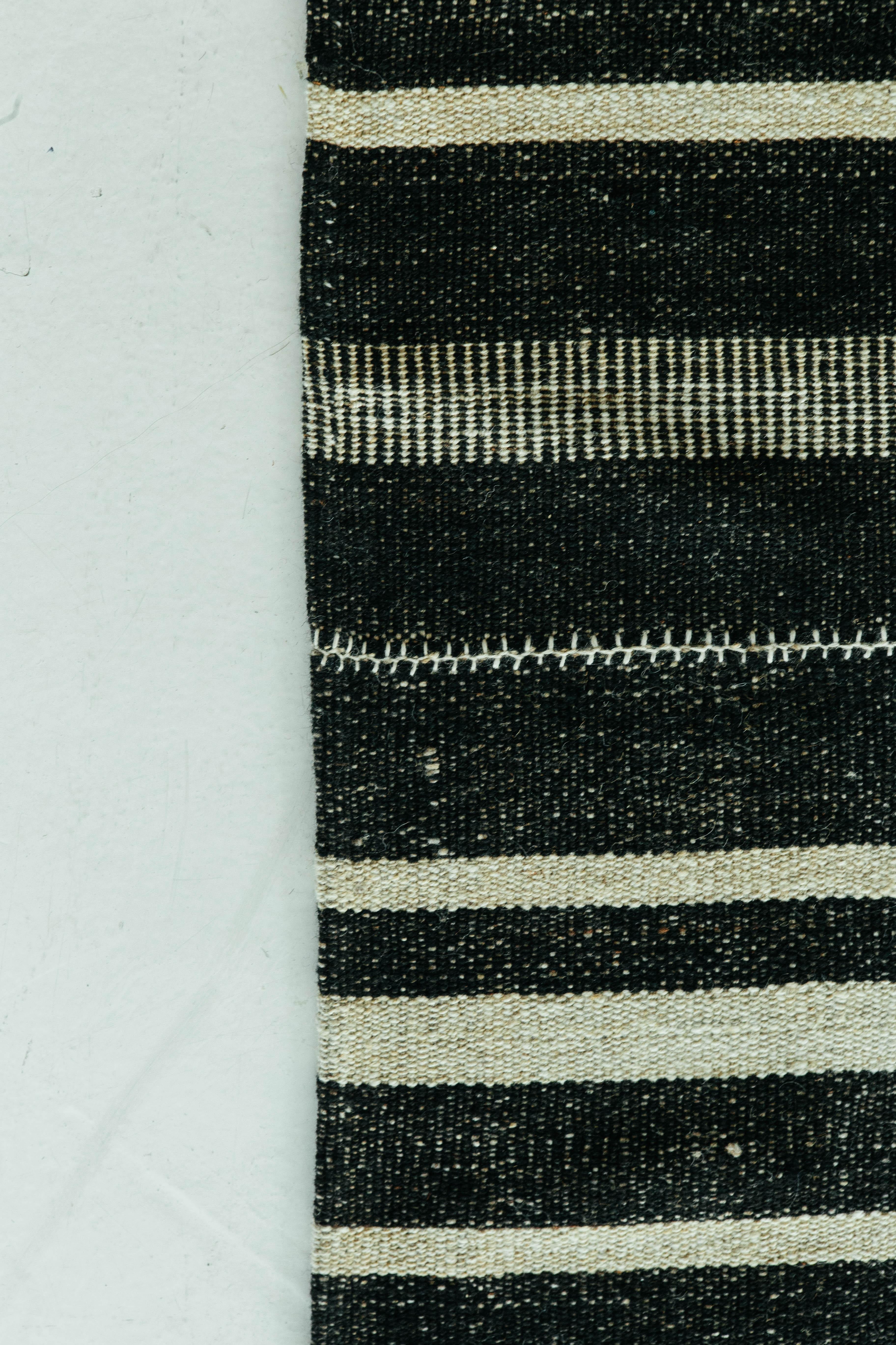Dieser persische Jejim-Kilim ist ein gebändertes Flachgewebe mit abwechselnd schwarzen und elfenbeinfarbenen Streifen in verschiedenen Größen und Ausführungen. Persische Flachgewebe bestehen aus der besten Wolle und werden auf außergewöhnliche Weise