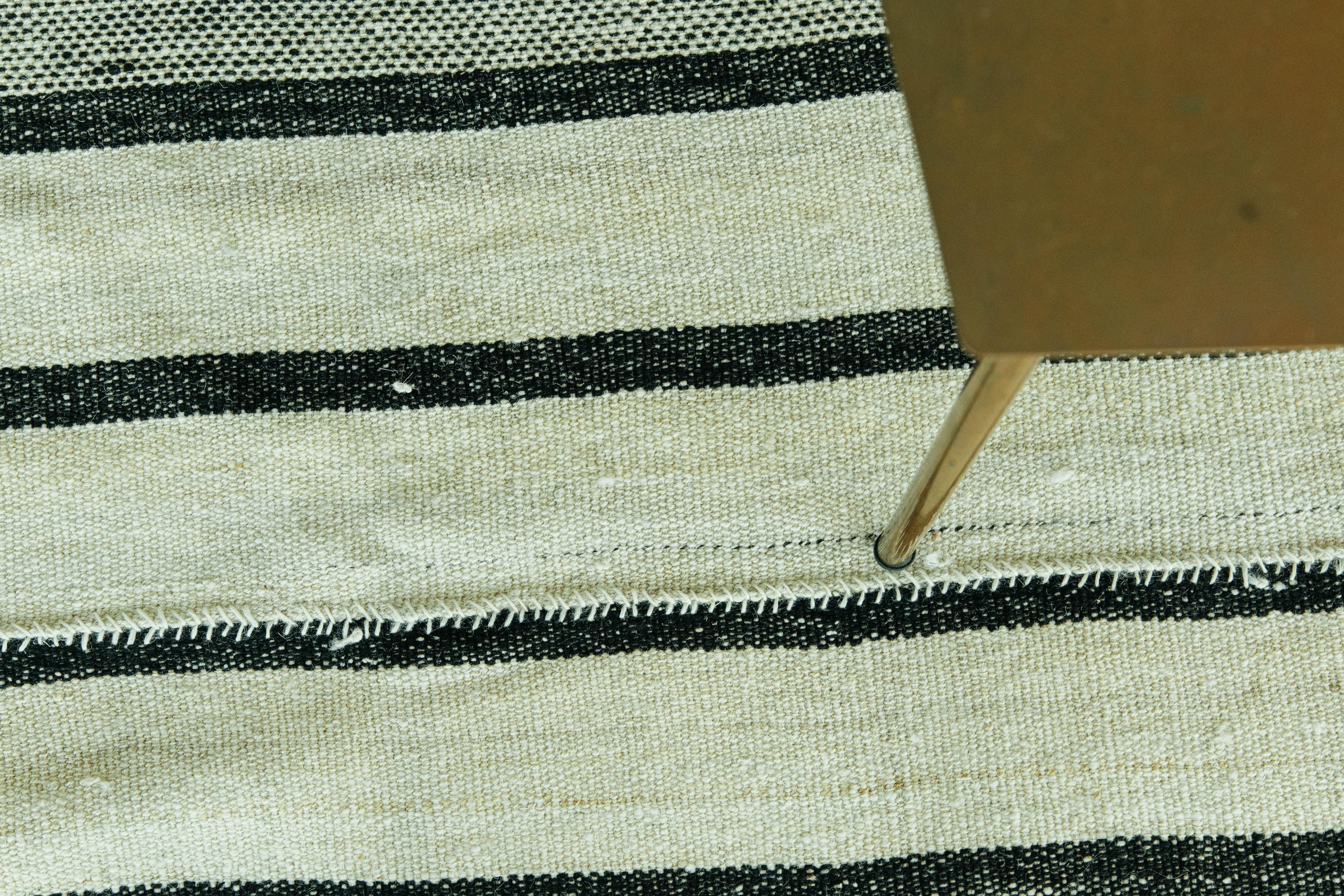 Dieser persische Jejim-Kilim ist ein gebändertes Flachgewebe mit abwechselnd dunkelbraunen und elfenbeinfarbenen Streifen in verschiedenen Größen und Ausführungen. Persische Flachgewebe bestehen aus bester Wolle und werden ausnahmsweise gewebt, um