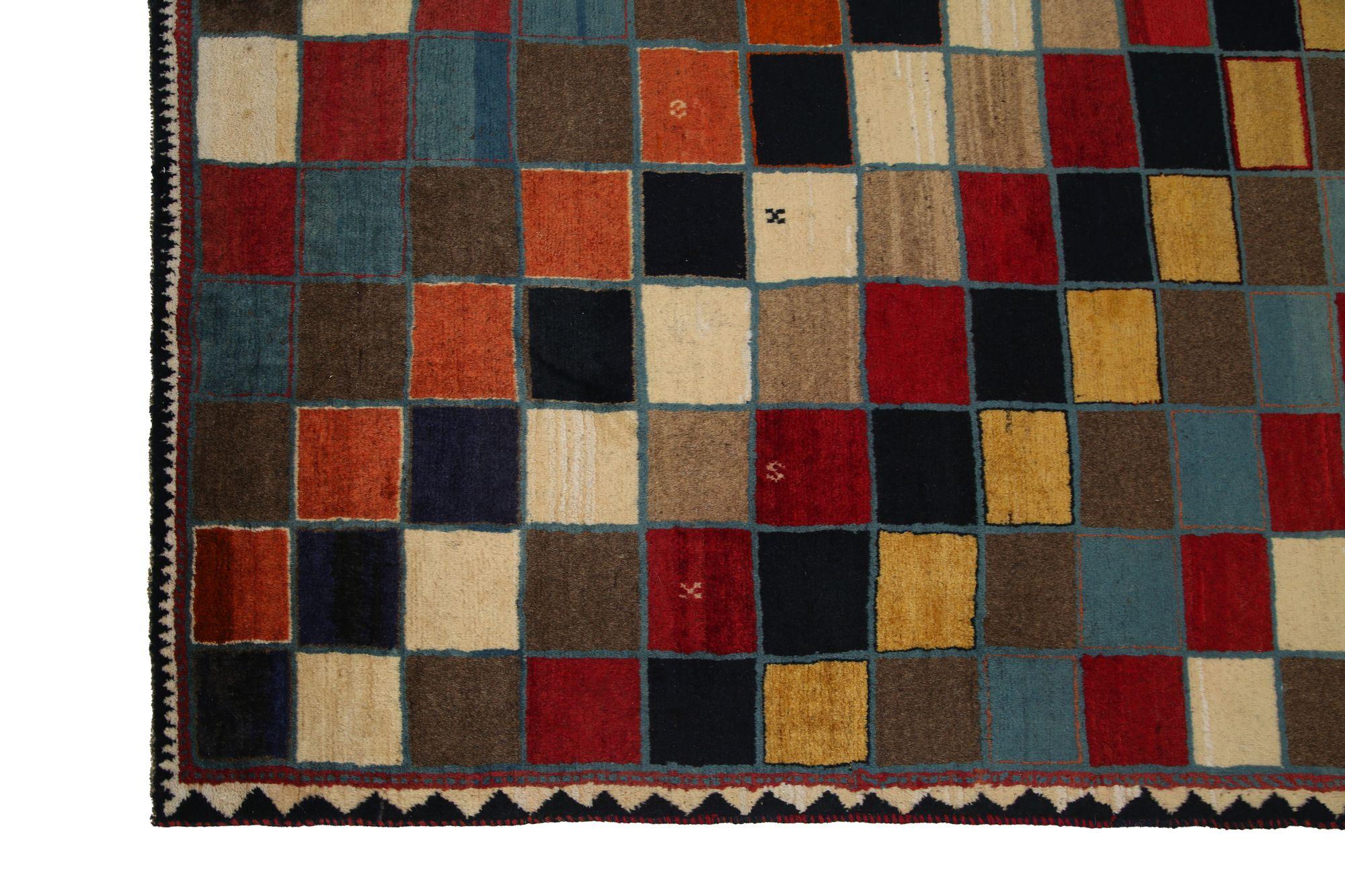 Entdecken Sie die Eleganz der persischen Gabbeh-Teppiche aus der Zeit um 1940. Dieses exklusive Design aus Wolle in den Farben SchwarzBlauBraunElfenbeinOrangeRotTaupeGelb ist perfekt, um Ihren Raum aufzuwerten.