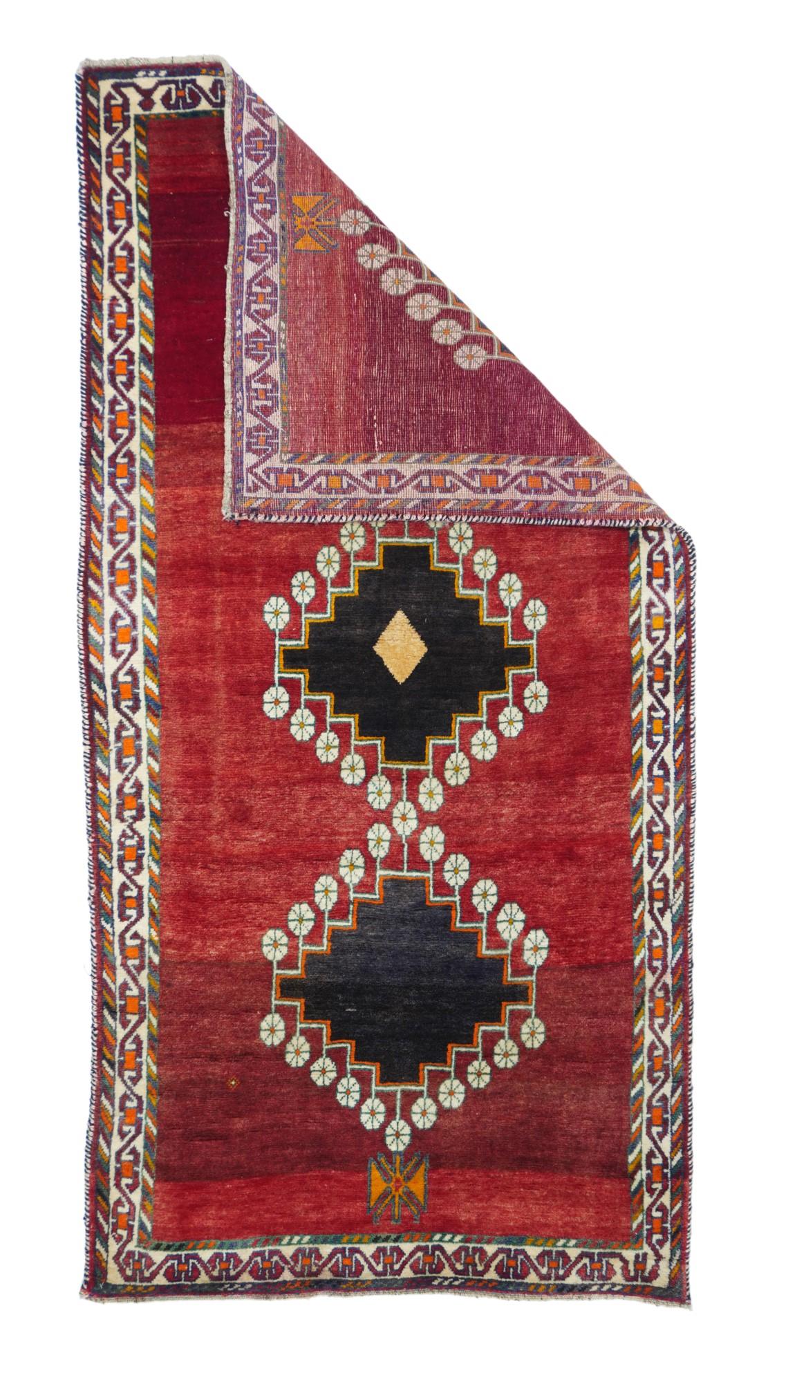 This SW Persian Qashghai tribal scatter shows an abrashed crimson open field centred by a pole medallion of three stepped near black diamonds, edged and joined by simple ecru rosettes. Main narrow ecru border with a reversing, linked rectangular 