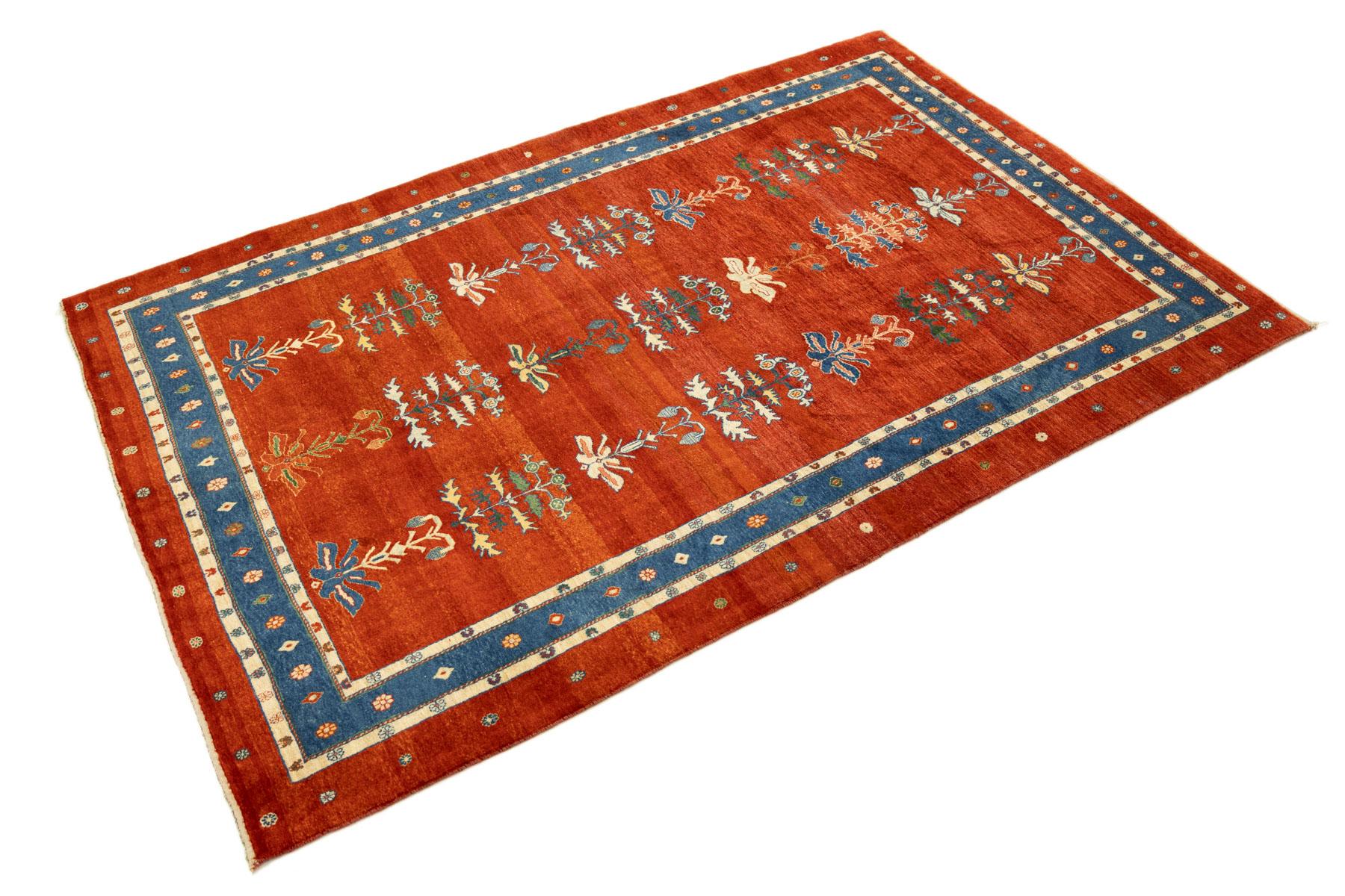 Persischer Gabbeh-Teppich, gewebt im Iran um 2000.

Dieser zeitgenössische Gabbeh zeigt ein warmes rostrotes Feld, das mit sich wiederholenden stilisierten Blumen- und Baummotiven verziert ist, die in einem ausgewogenen Gitter angeordnet sind.