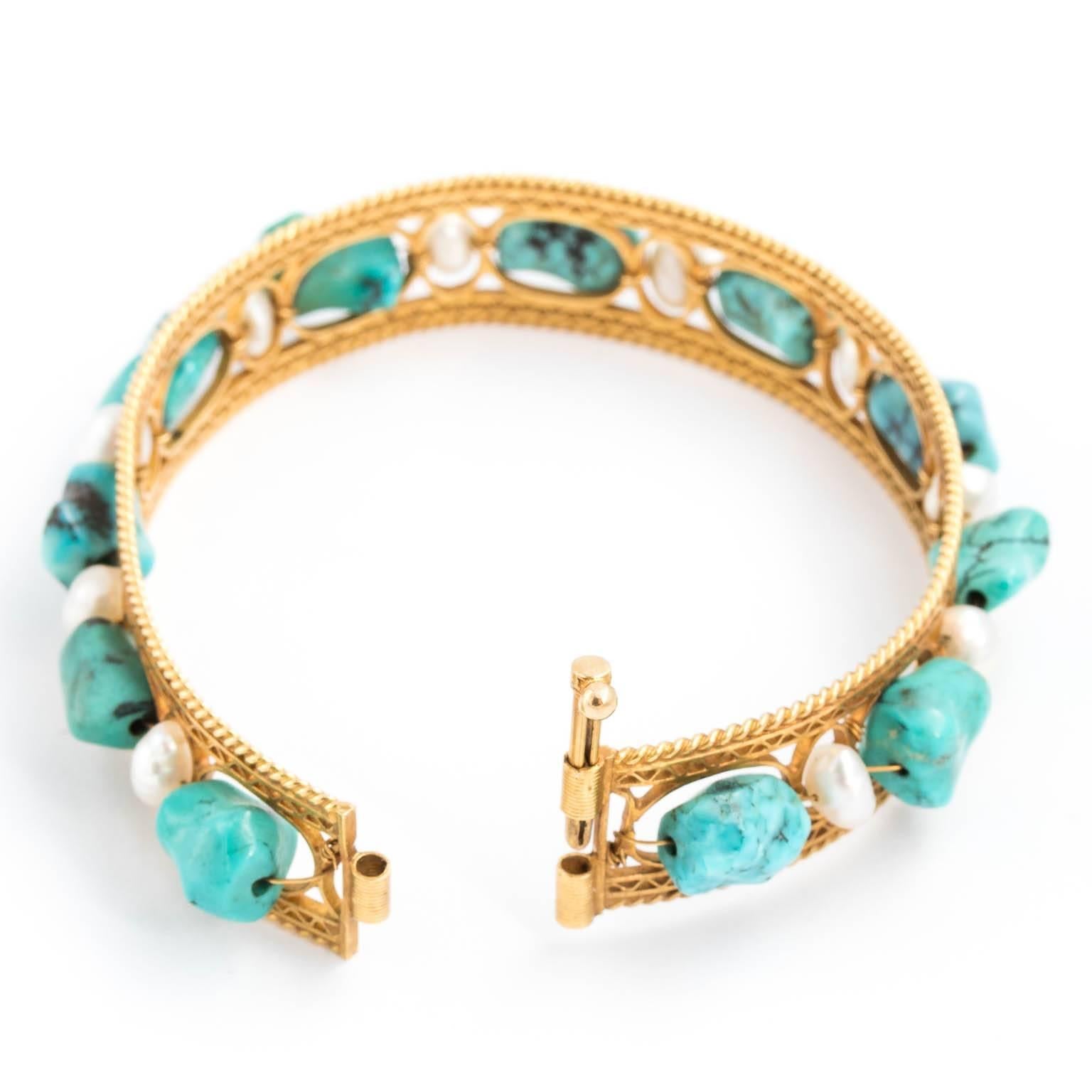 Circa 1930-1950 18 karat gold bangle with natural Persian turquoise and cultured pearls. An 18 karat bangle from circa 1930-1950 using open work design on edges with large Persian Turquoise pieces interspersed with cultured pearls around the