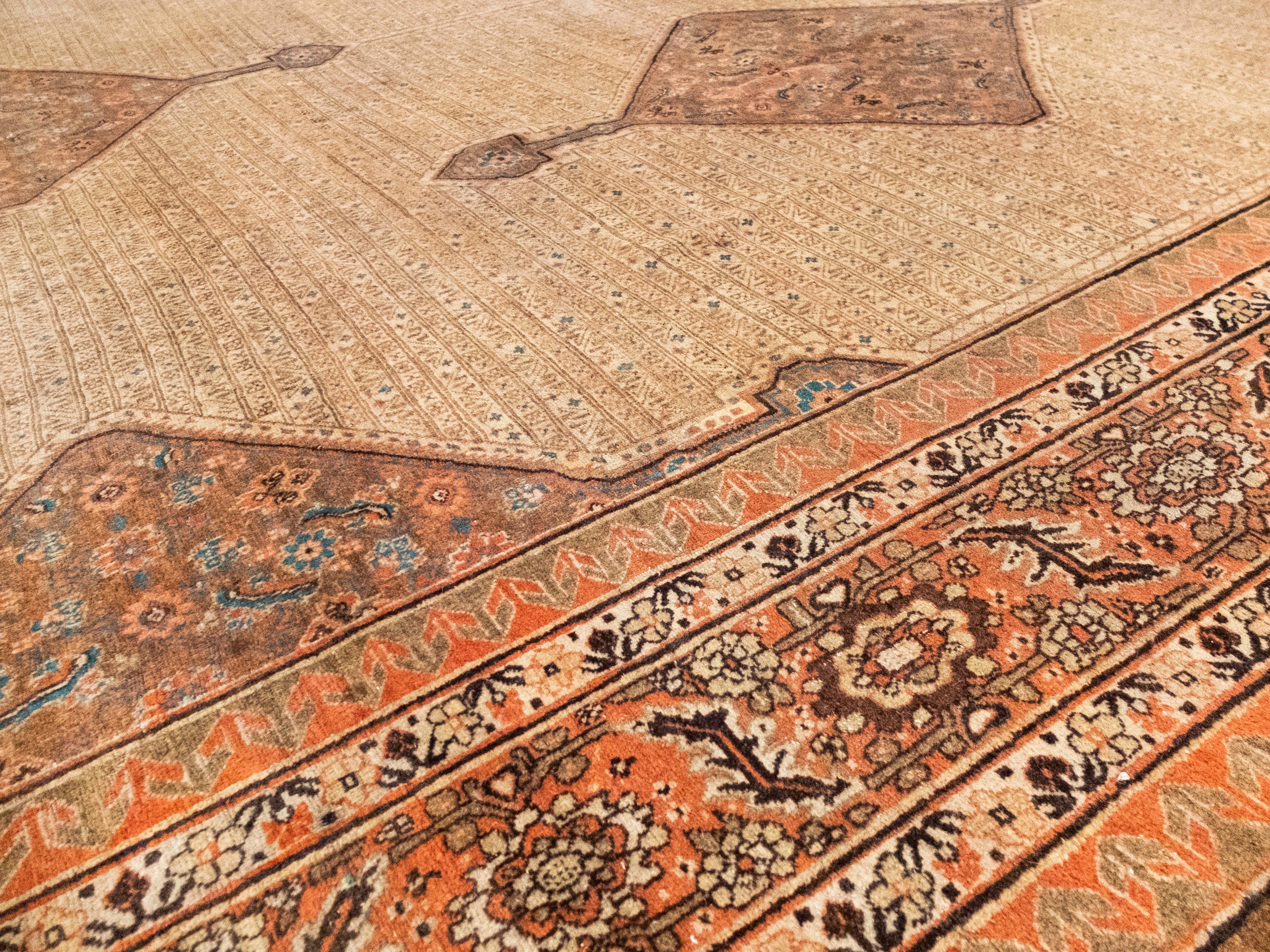 This is a Haji Jalili Tabriz rug meaning it comes from some of the most high-quality mill/houses of its time. It displays exquisite earth tones such as tan, reddish browns, and burnt sienna. Its main field has 5 diamond geometric shapes and inside